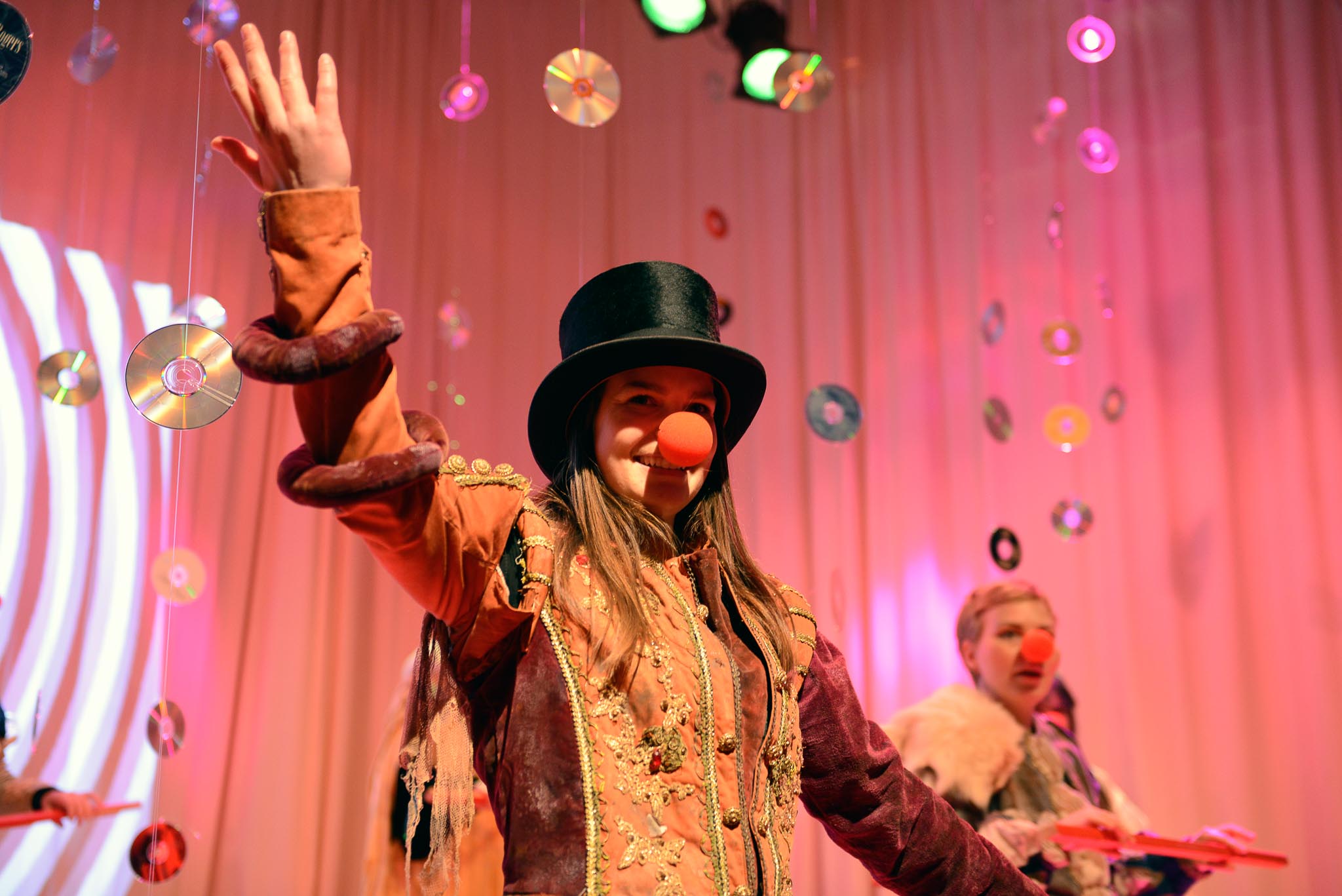 Bilde av jente med flosshatt og klovnenese på en scene.