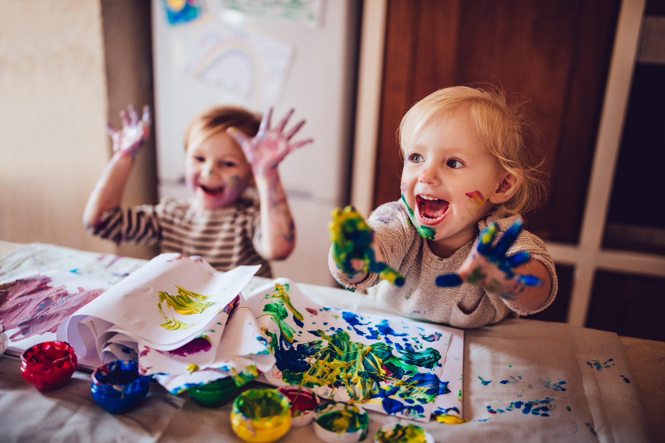 To smilende små barn maler med hendene