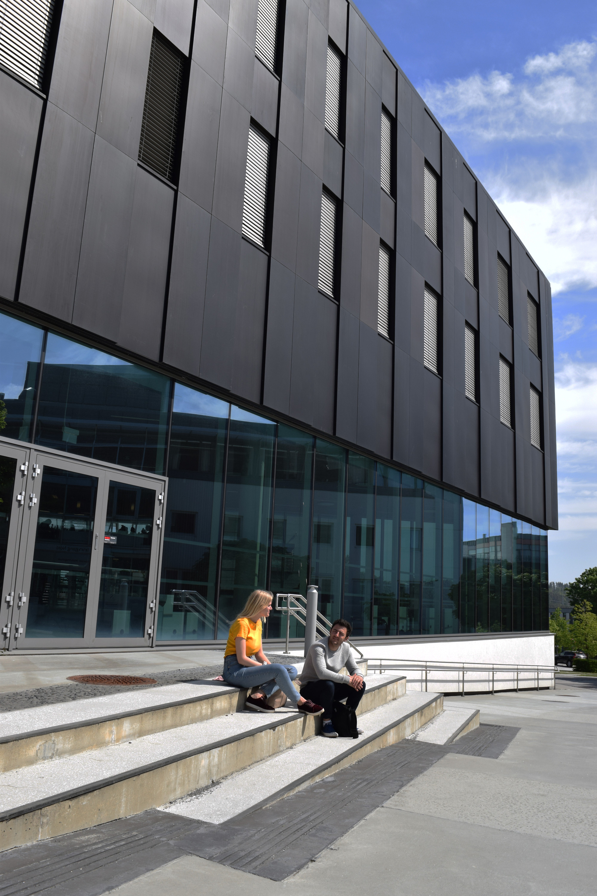 To studenter sitter på trappen utenfor Elise Ottesen-Jensens hus.