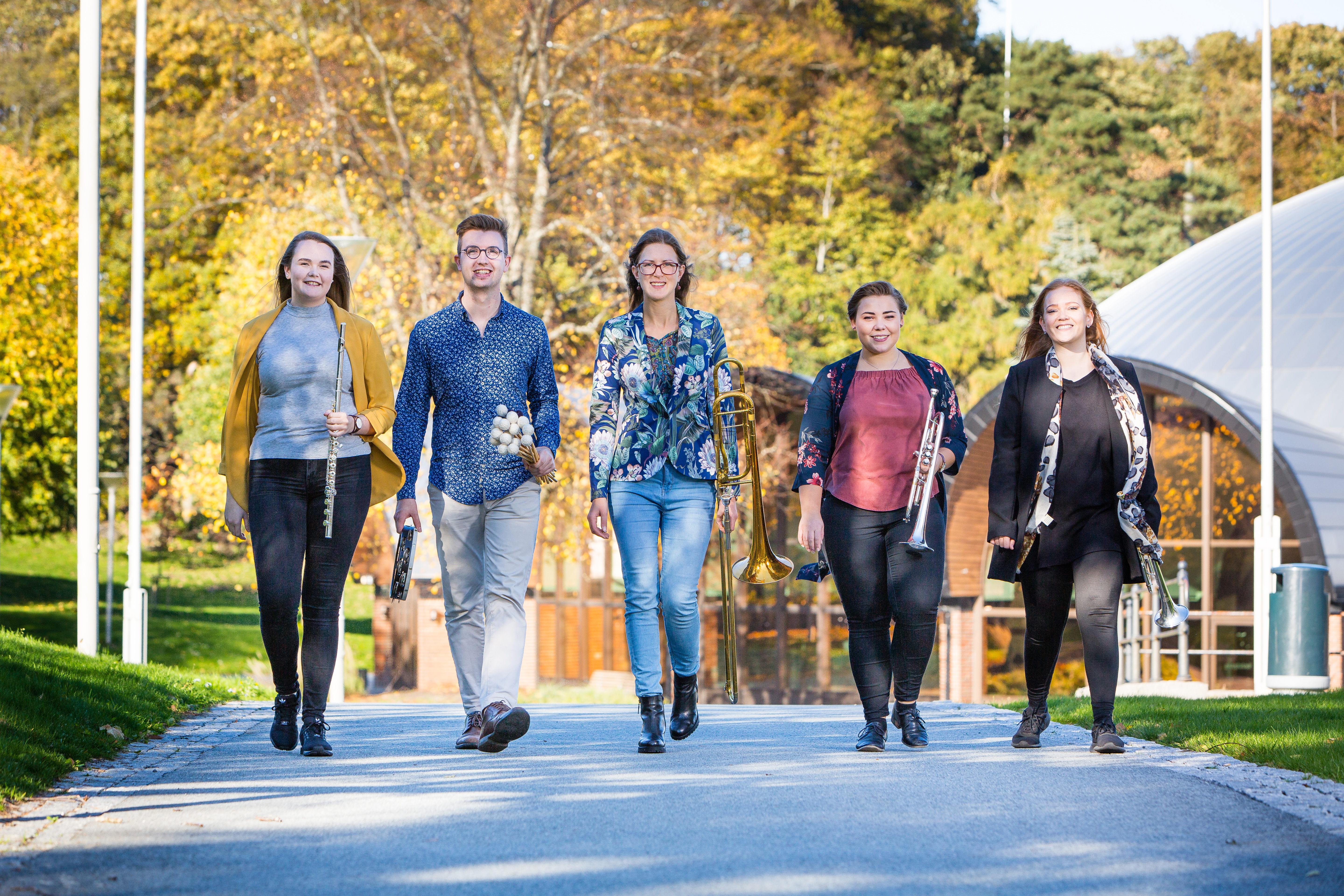 Fem studenter som går med hvert sitt instrument