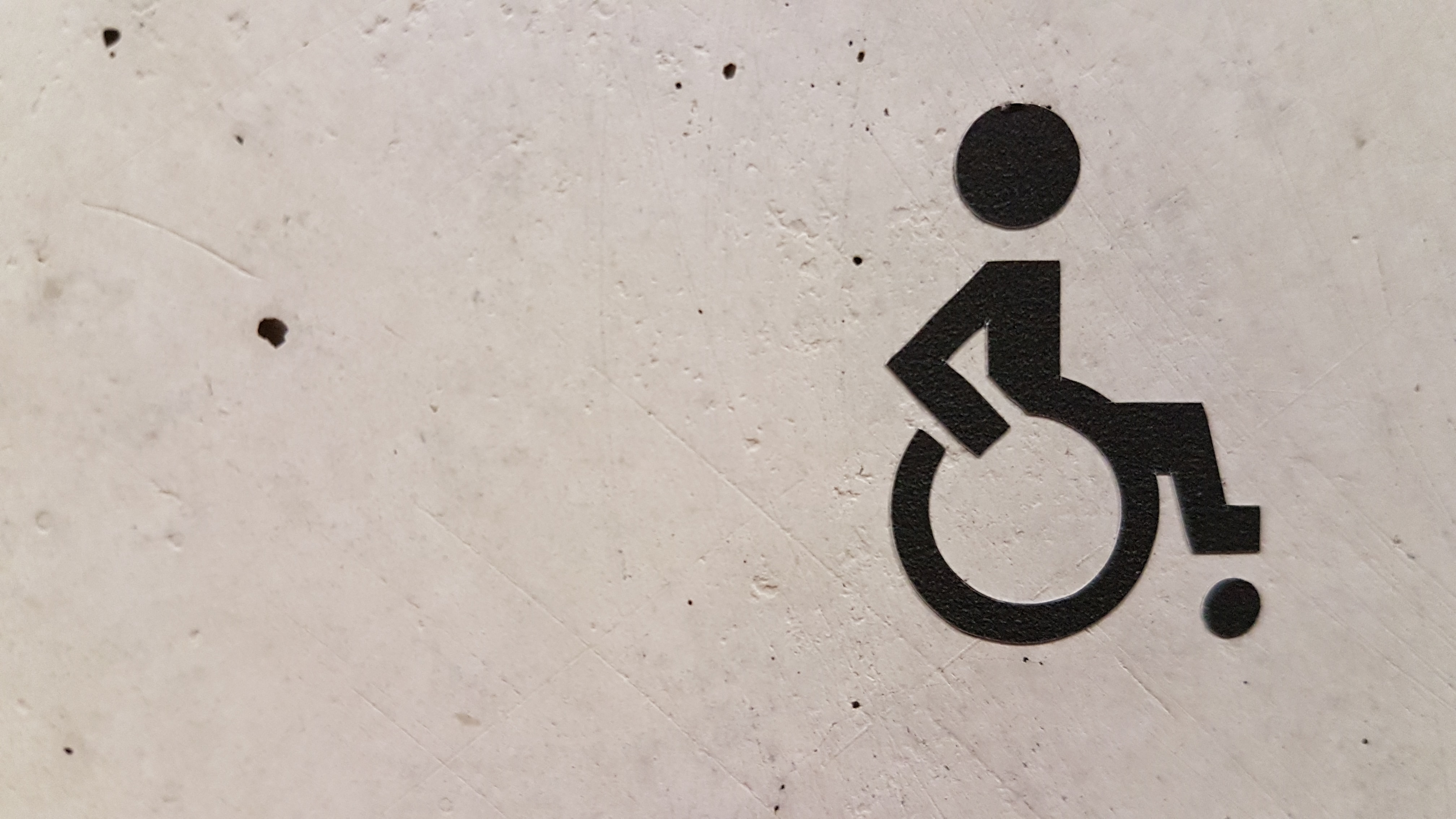 Photo of a wheel chair illustration on a concrete wall. 