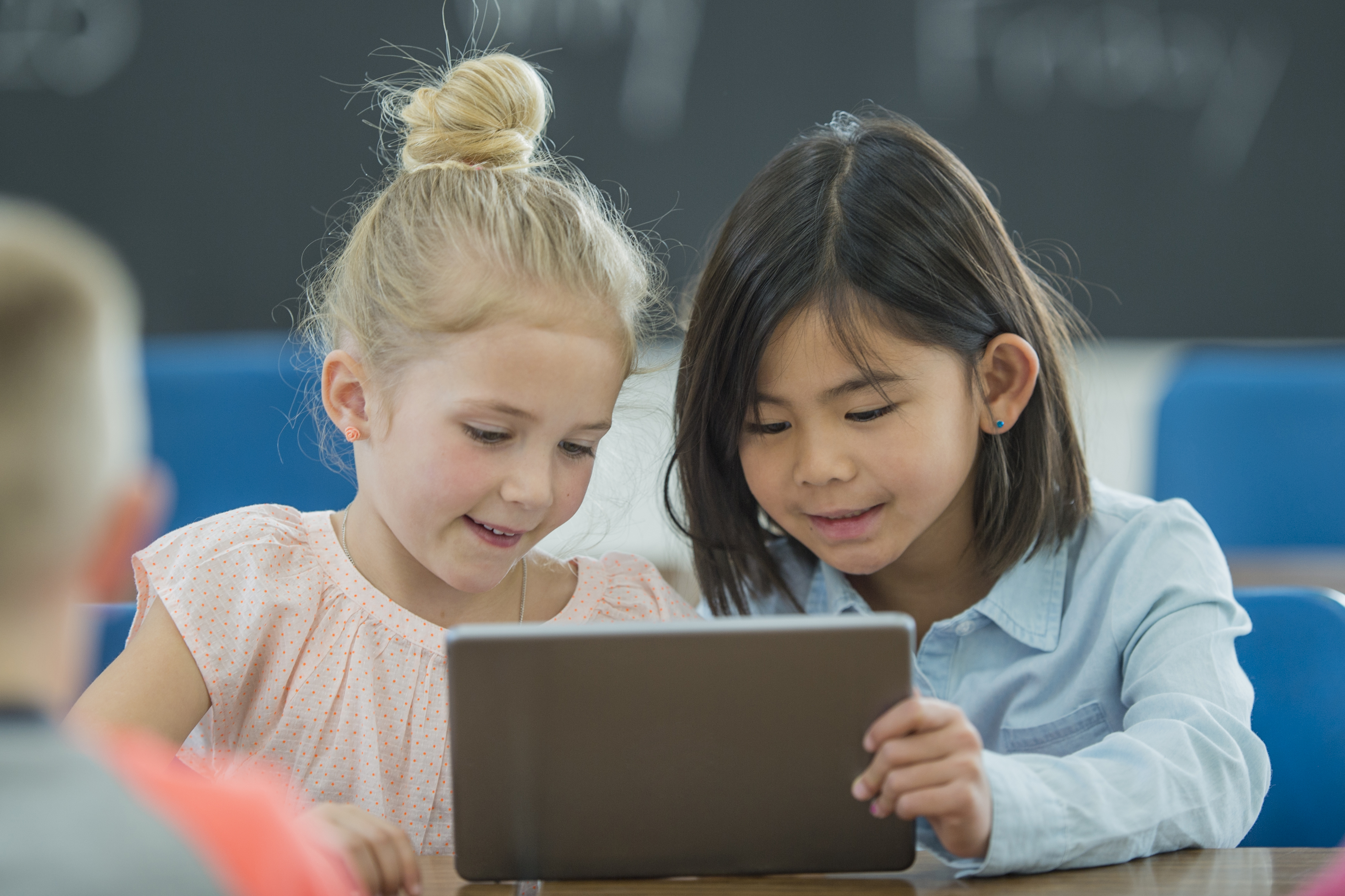 To små jenter ser på en ipad sammen i et klasserom