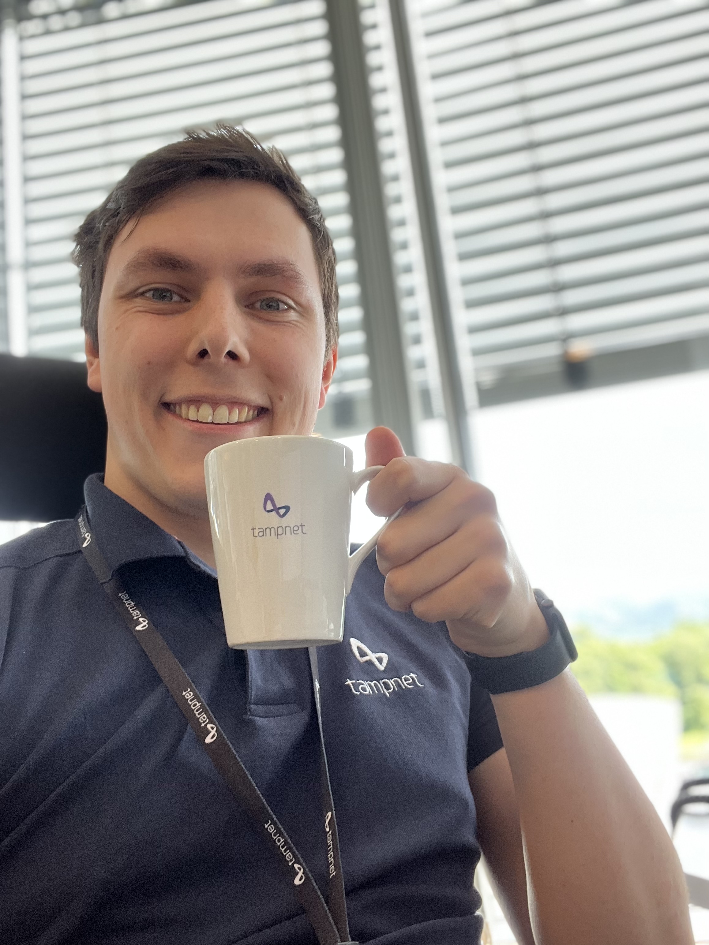 Mann med svart t-skjorte som holder en kaffekopp. Foto.