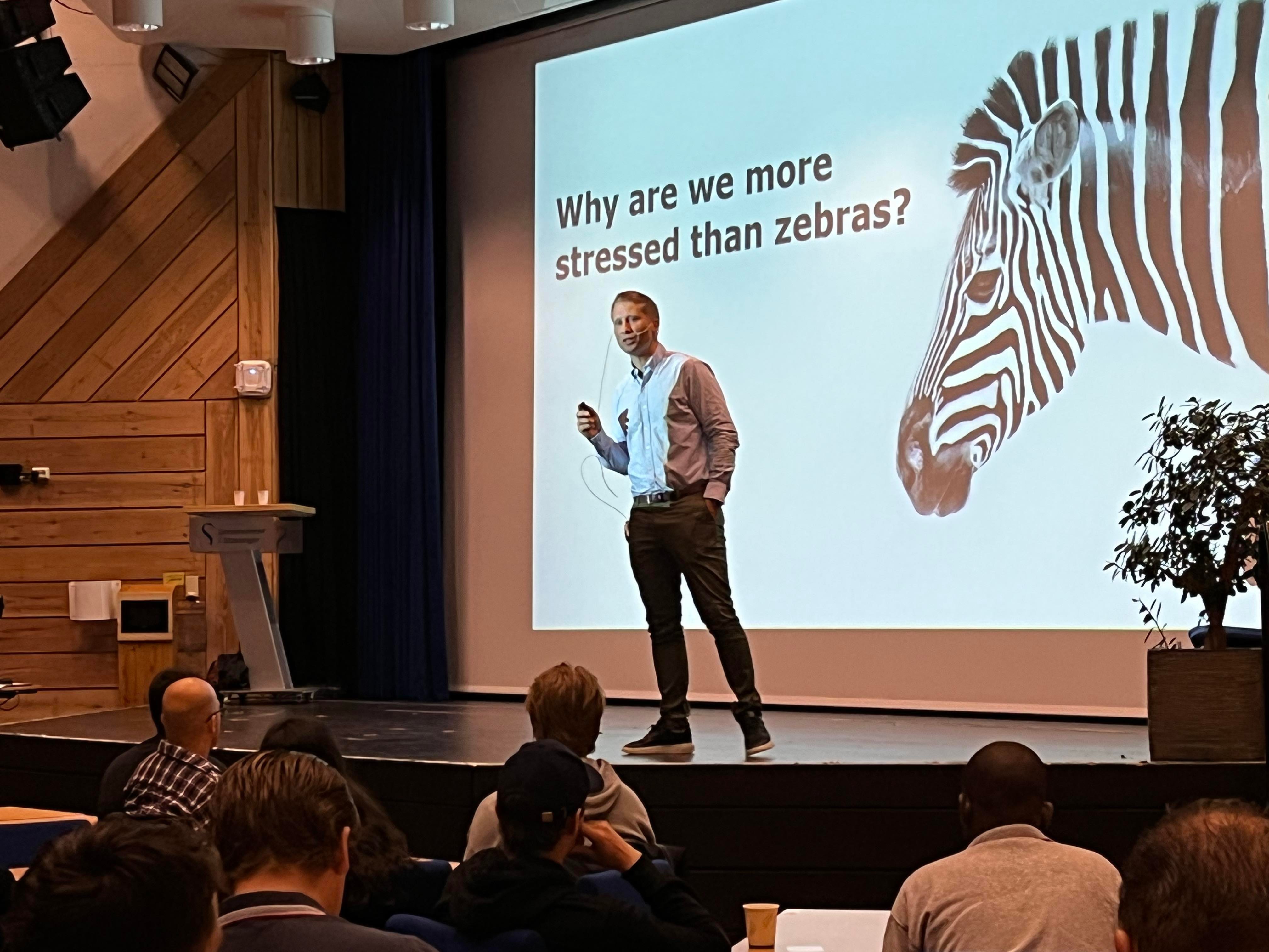 Erlend Rørvik underviser masterstudenter i å mestre stress. På skjermen står det "Why are we more stressed than zebras"