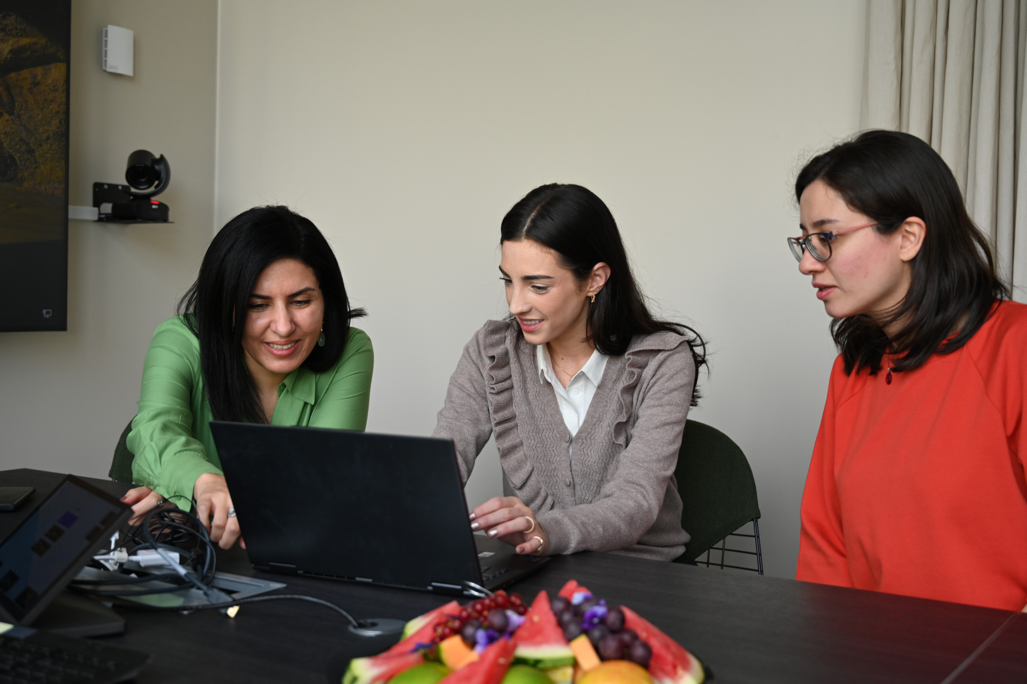 3 kvinner prater sammen foran en datamaskin