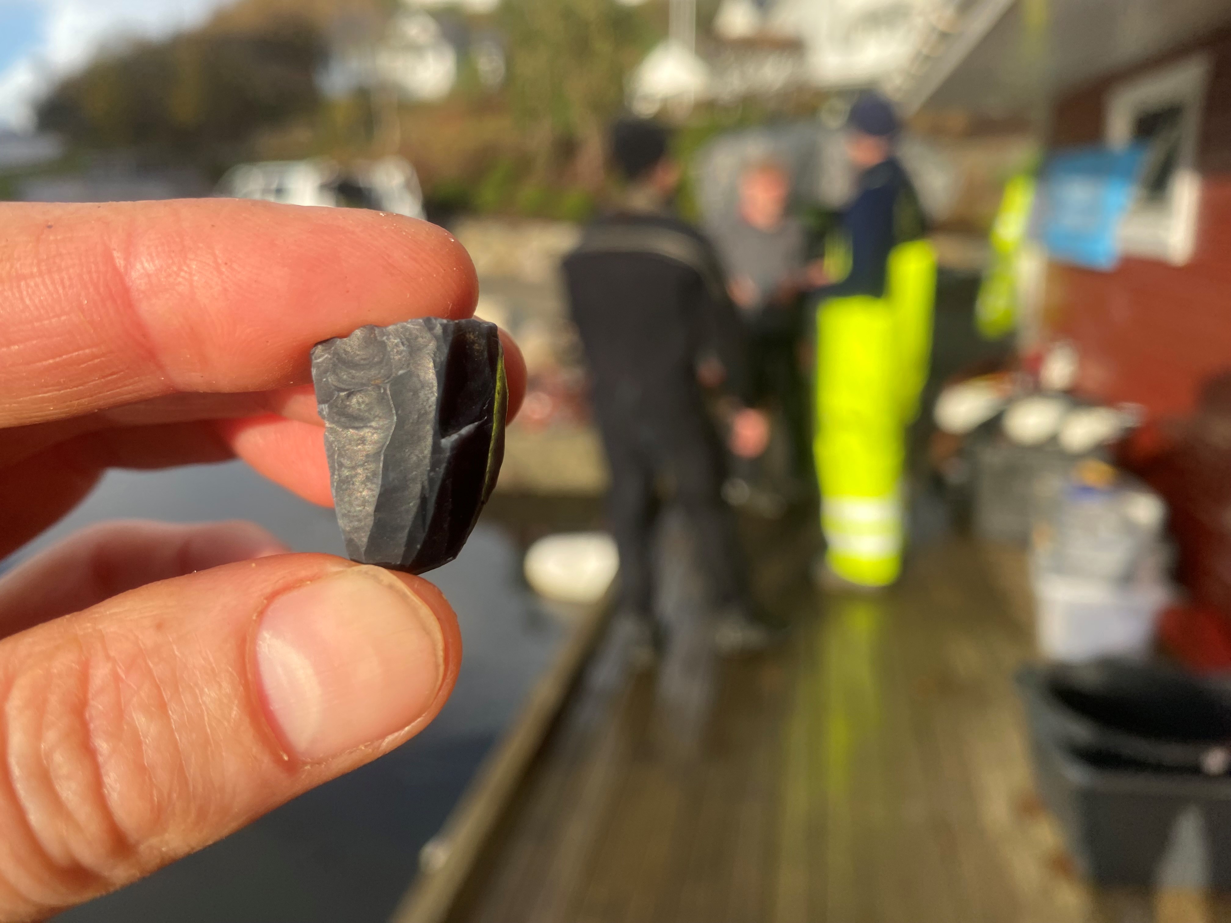 Et flintredskap dukker opp blant massene fra havbunnen. 