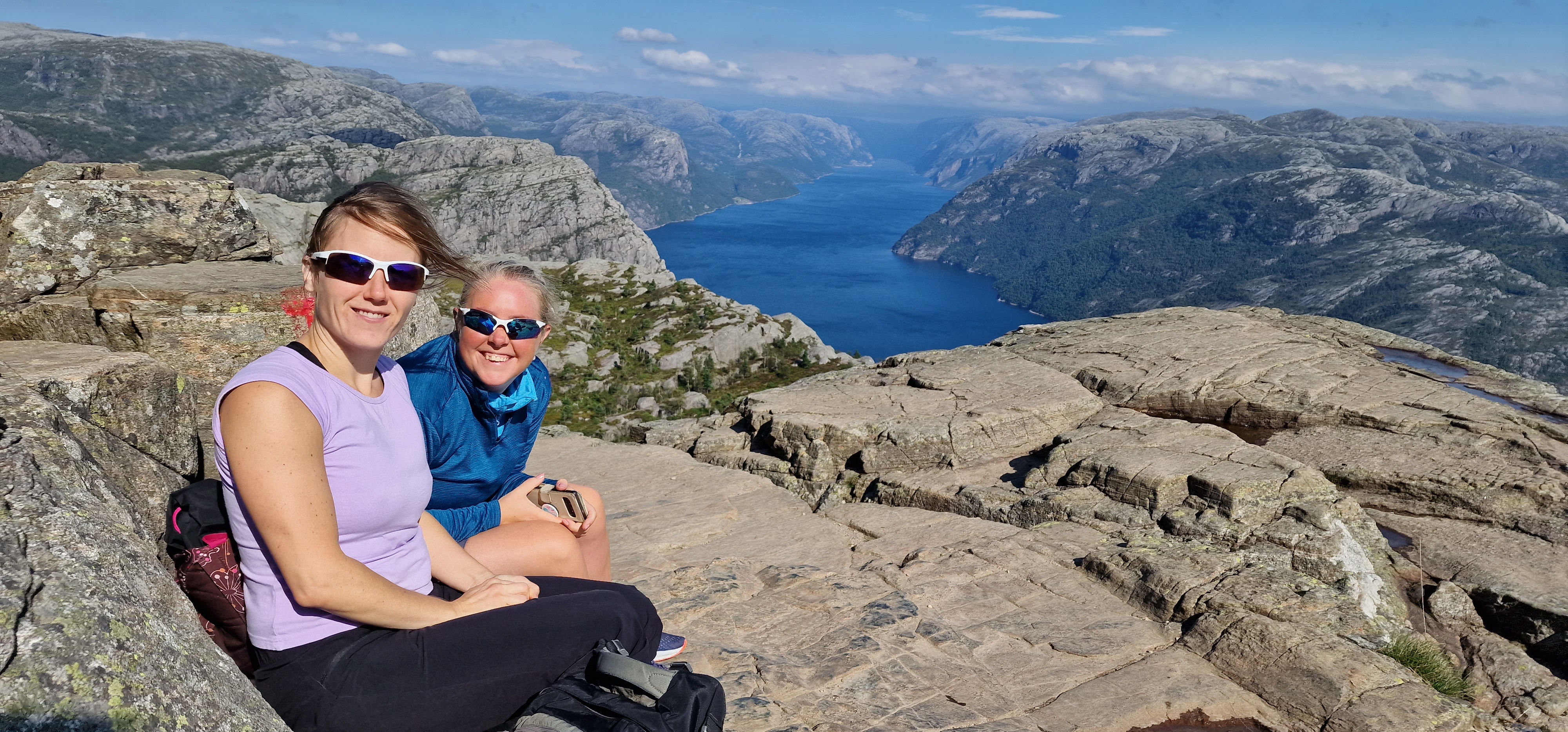 To kvinner i turklær på Preikestolen med utsikt over Lysefjorden i bakgrunnen