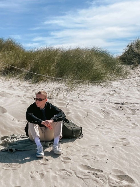 Eirik Hjorth Kjelvik som sitter i en sanddyne.