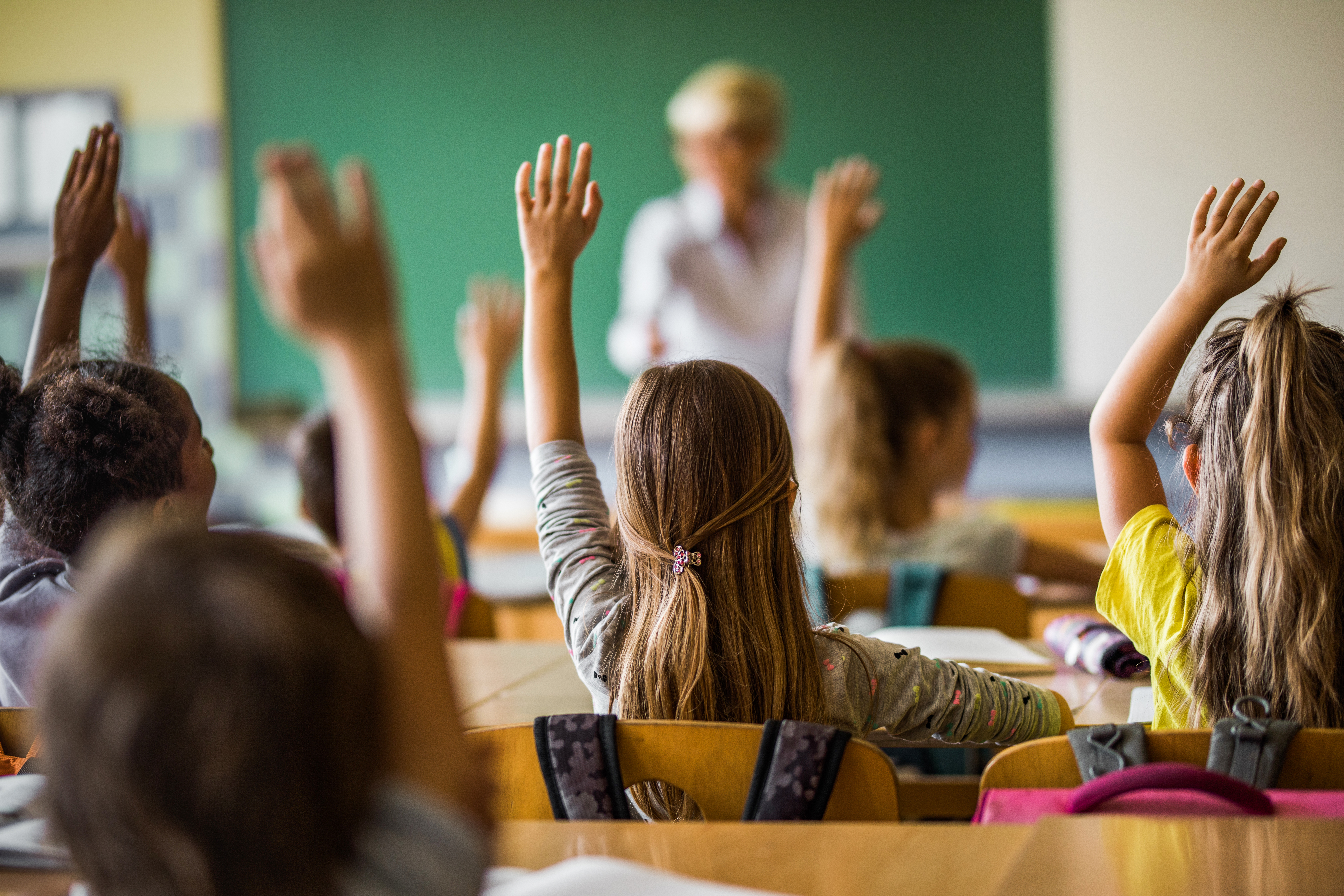 Barn i et klasseom rekker opp hendene