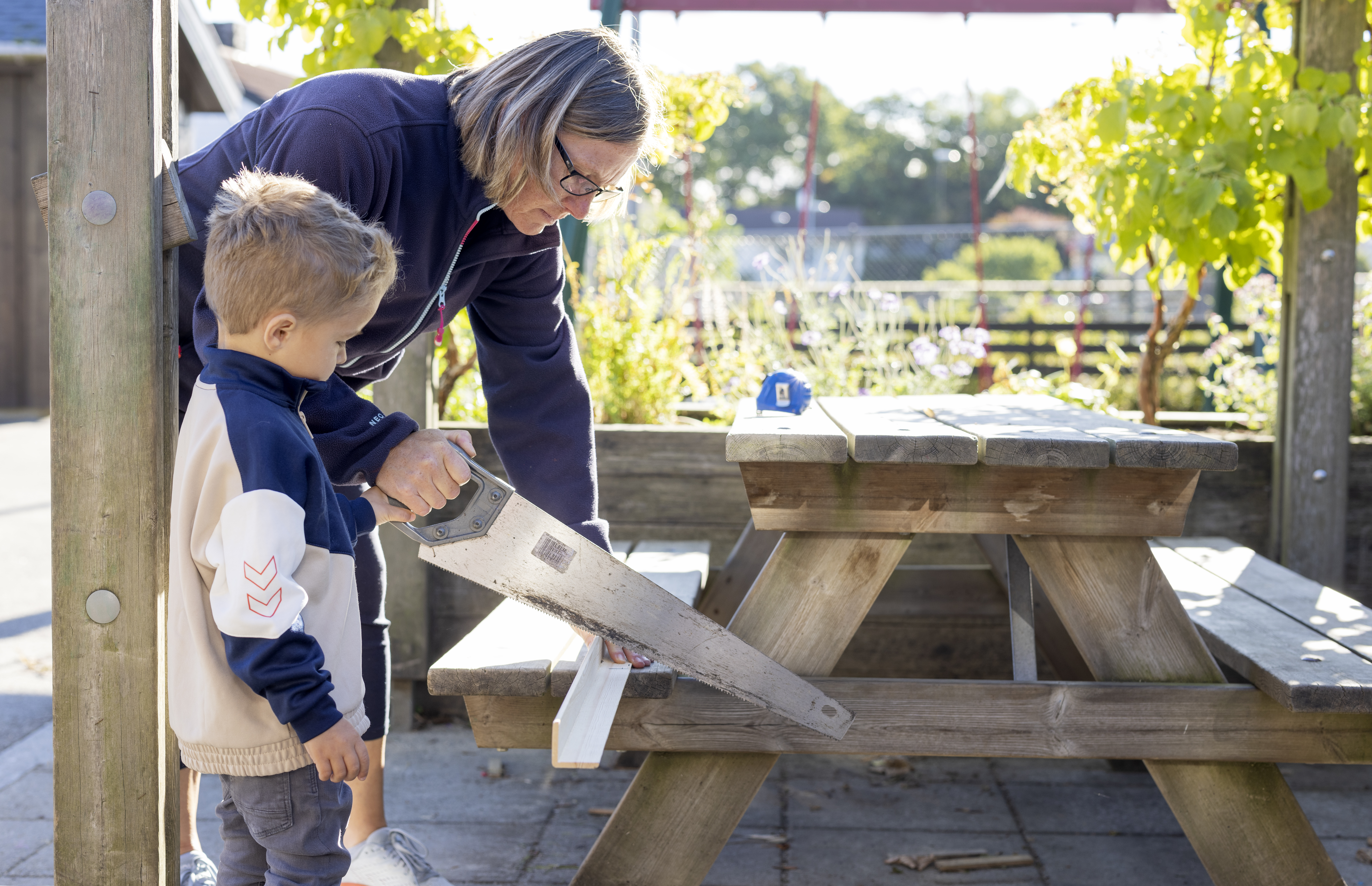 En kvinne og et barn sager en planke. Foto: Elisabeth Tønnessen/Læringsmiljøsenteret, UiS