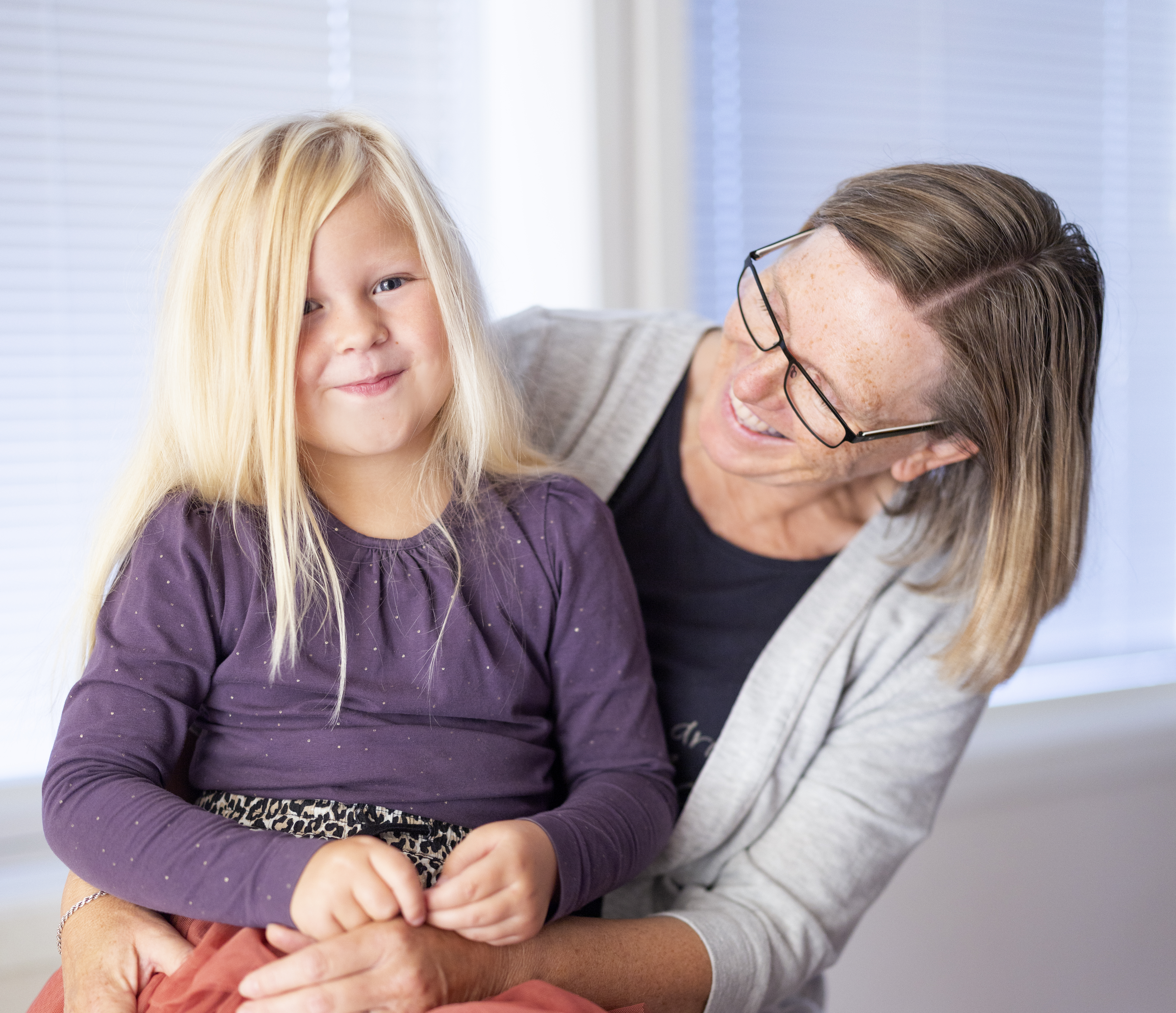 Et lite barn sitter på fanget til en kvinne. Begge smiler. Foto: Elisabeth Tønnessen/Læringsmiljøsenteret, UiS