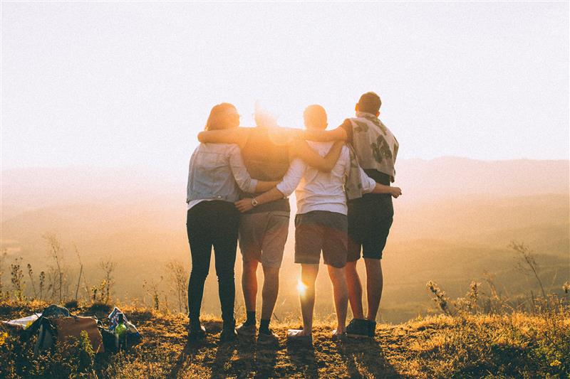 Studenter som klemmer i solnedgang 