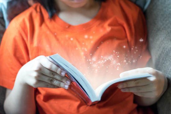 nærbilde av barn som holder en bok. bildet er tatt fra halsen og ned.
