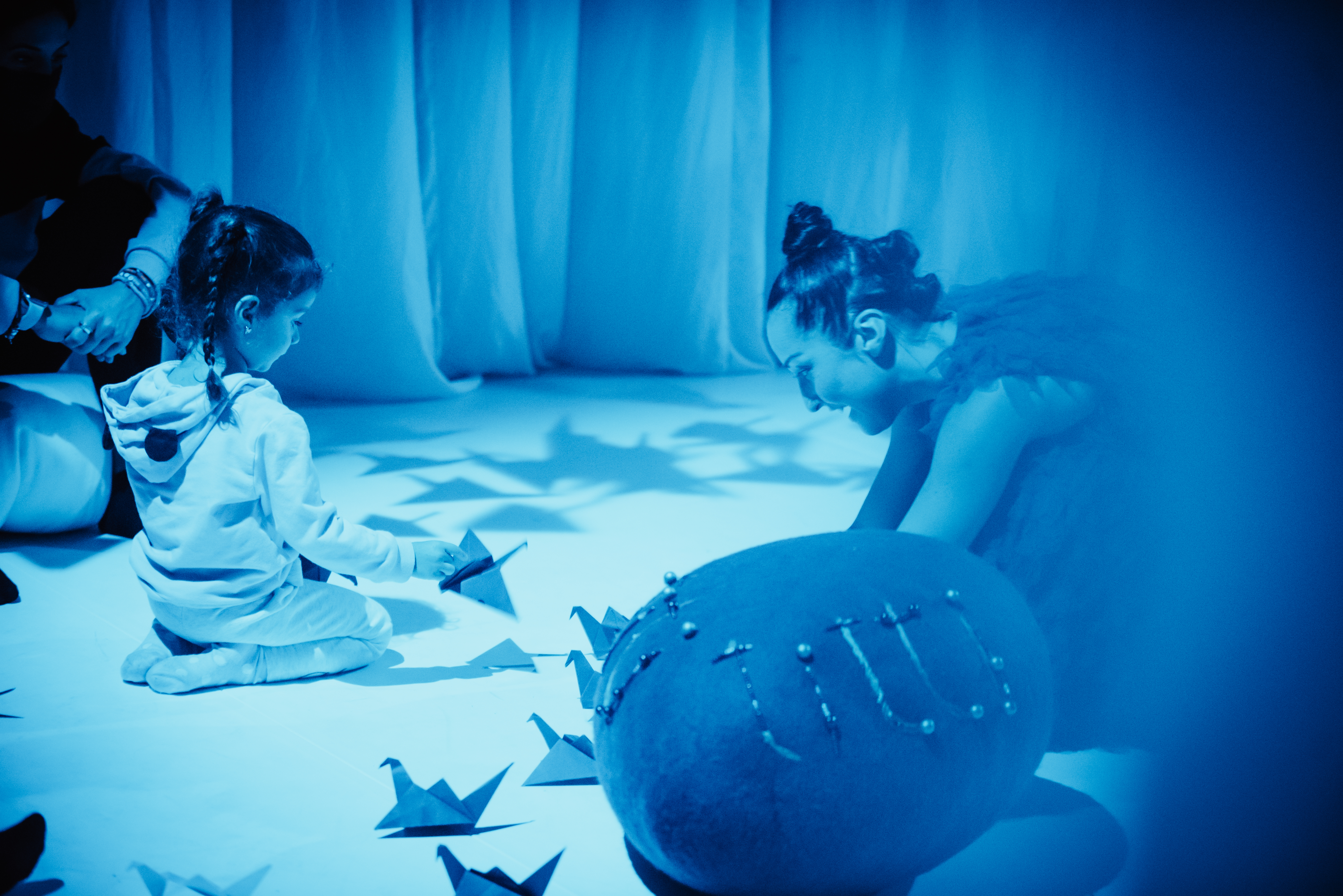 Scenekunstner sitter på gulvet og leker med et barn