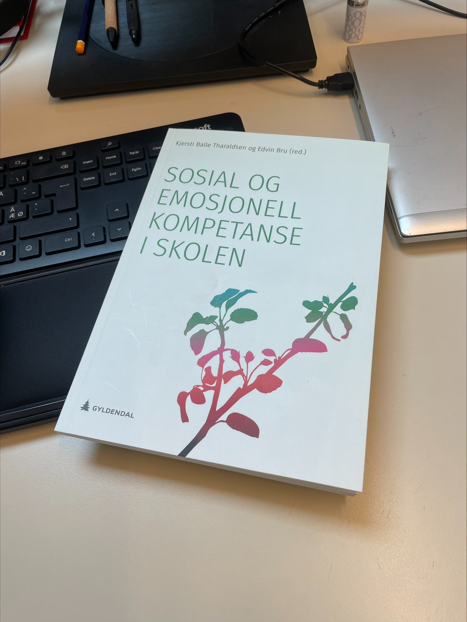 Boken Sosial og emosjonell kompetanse i skolen ligger på et skrivebord.