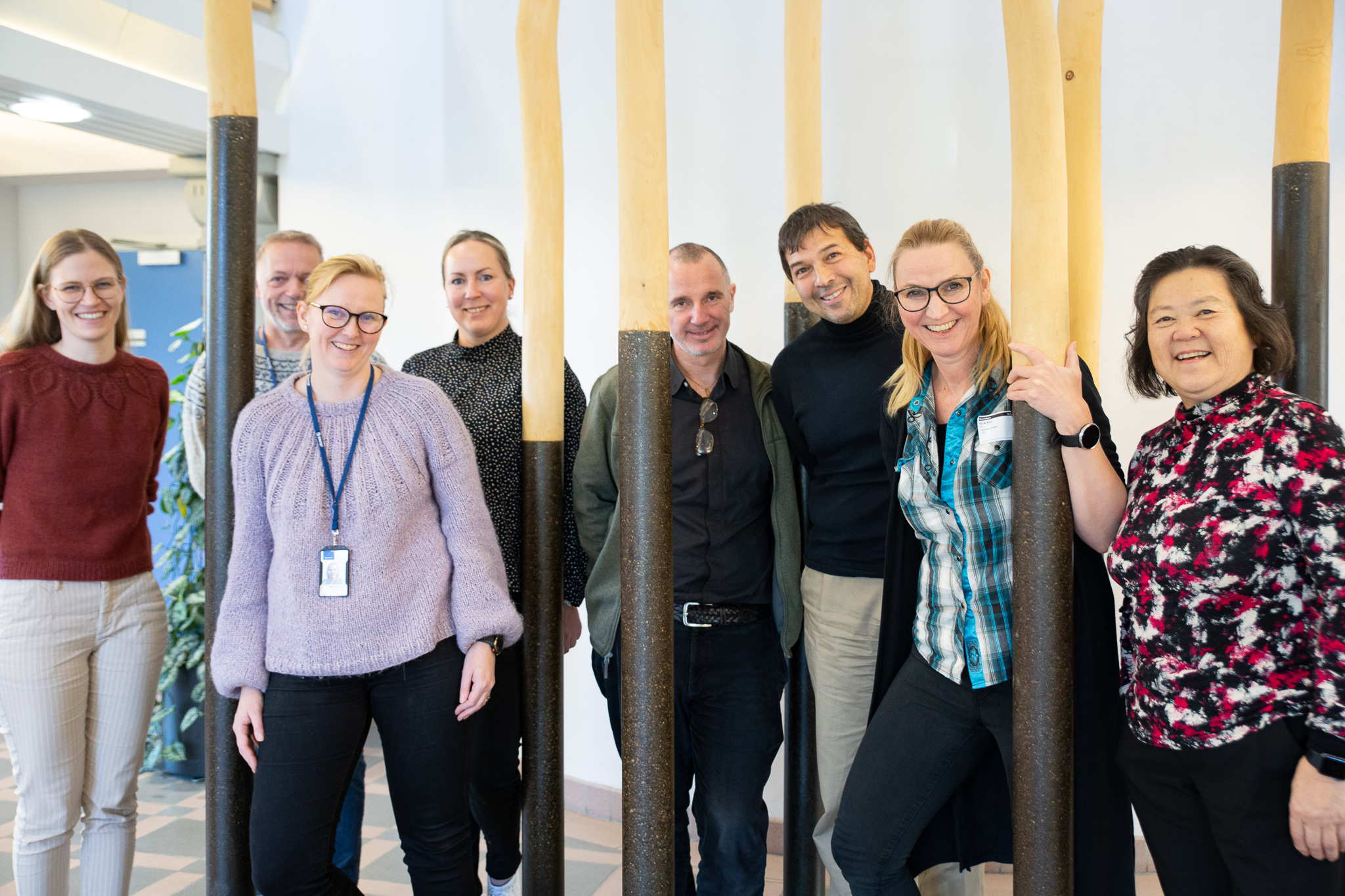 En gruppe mennesker poserer ved et kunstverk av søyler.