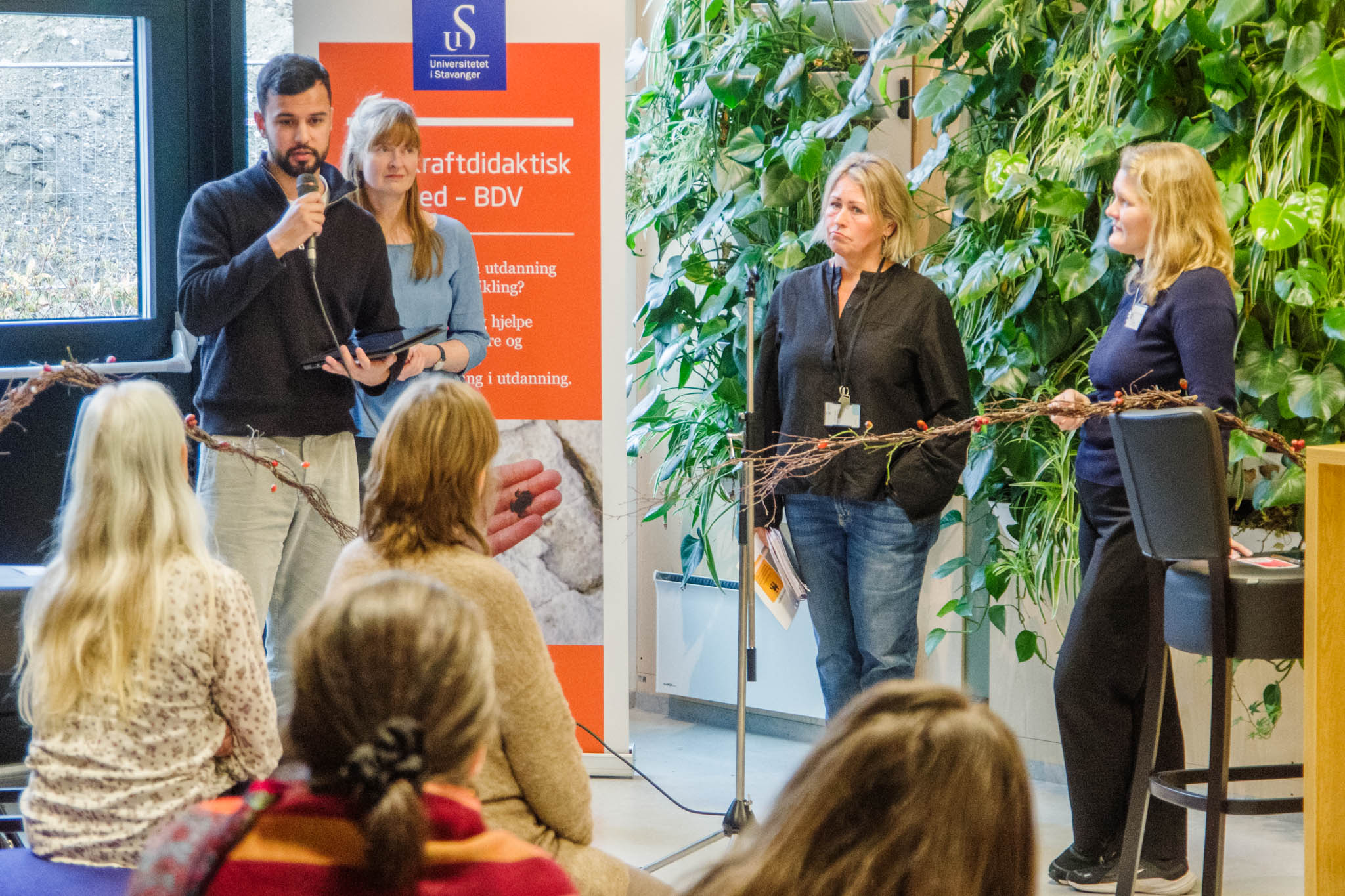 mennesker på en scene, en mann snakker i mikrofon