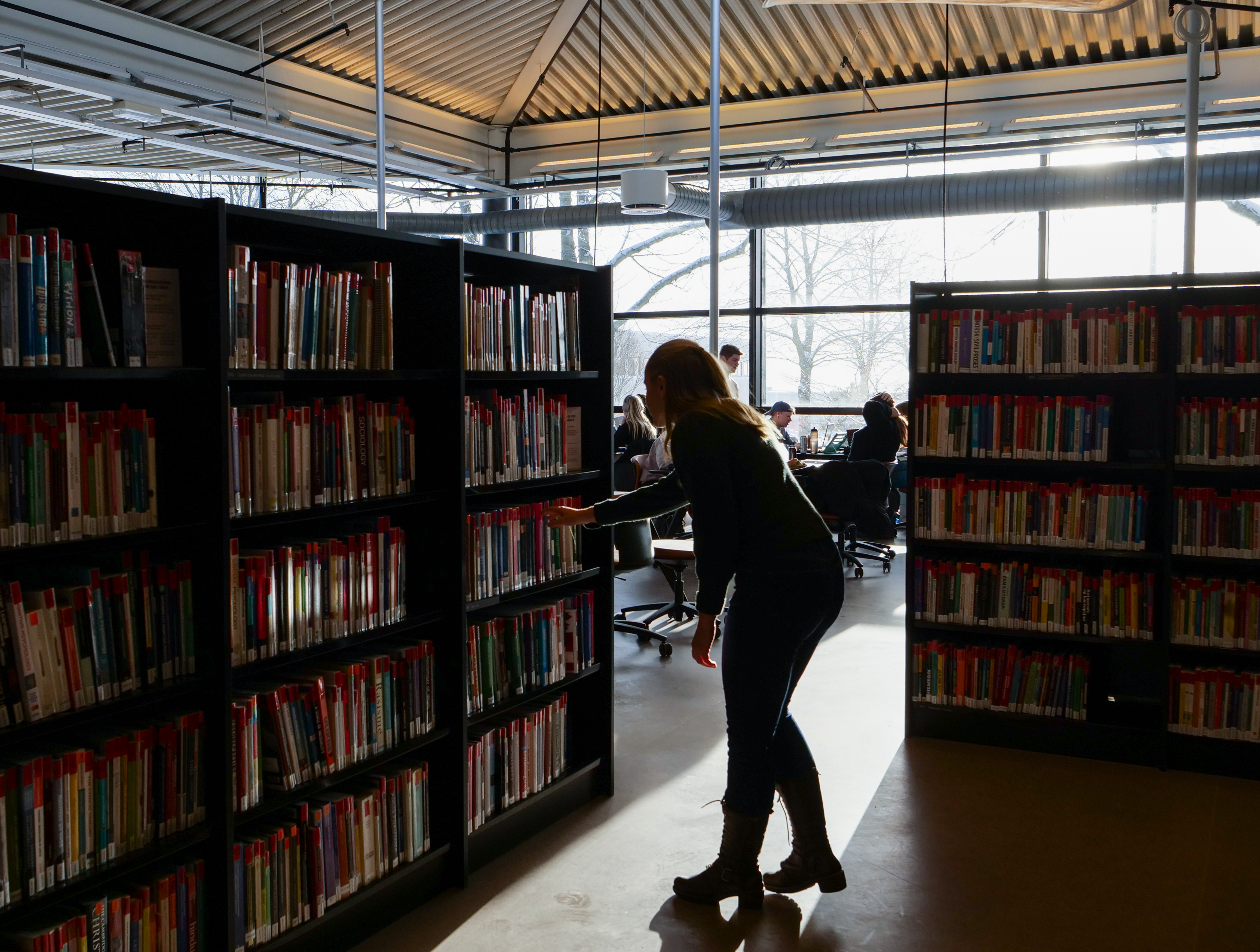 Student leter etter bøker i bokhyllen