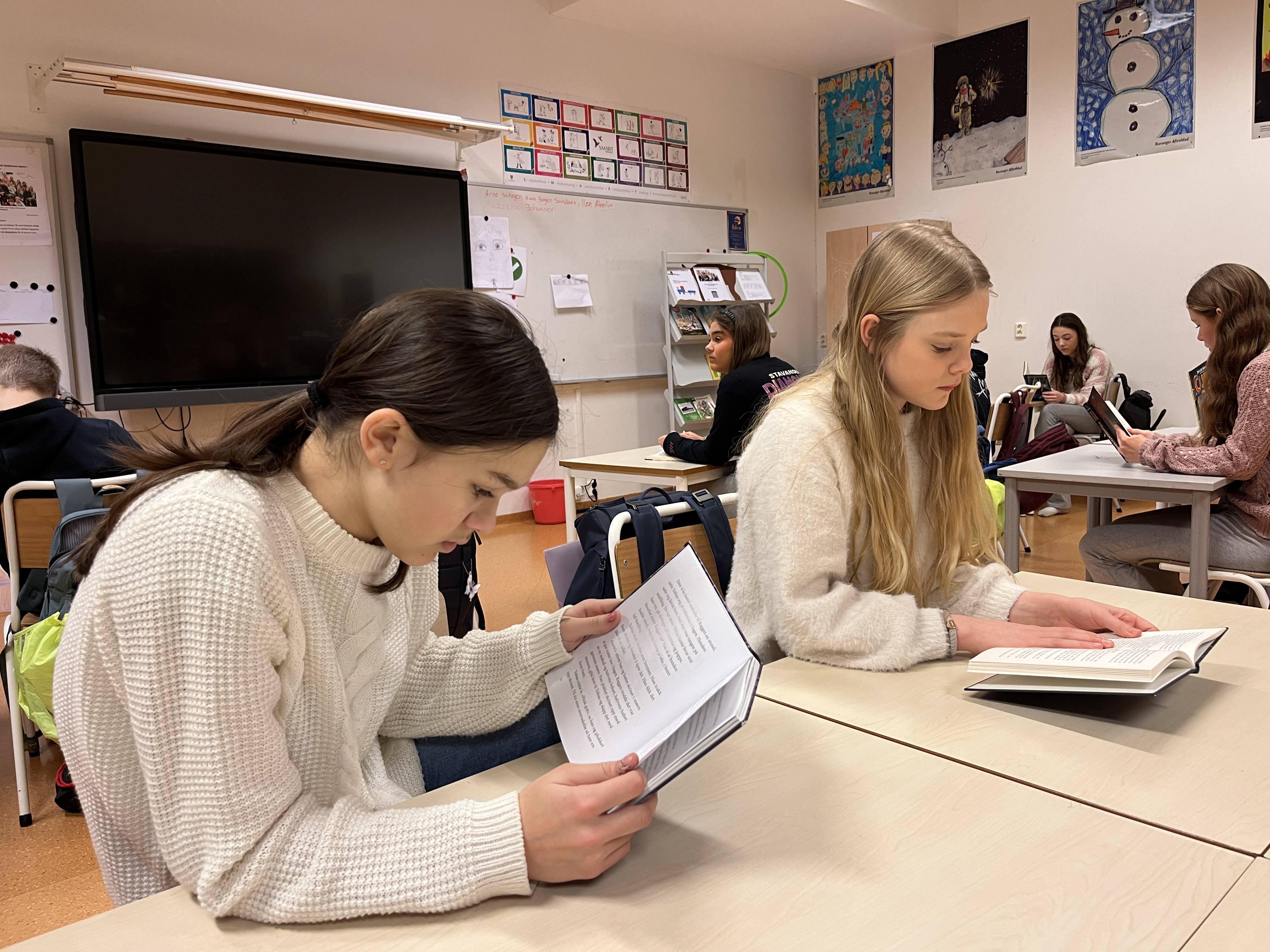 To jenter leser hver sin bok i klasserommet