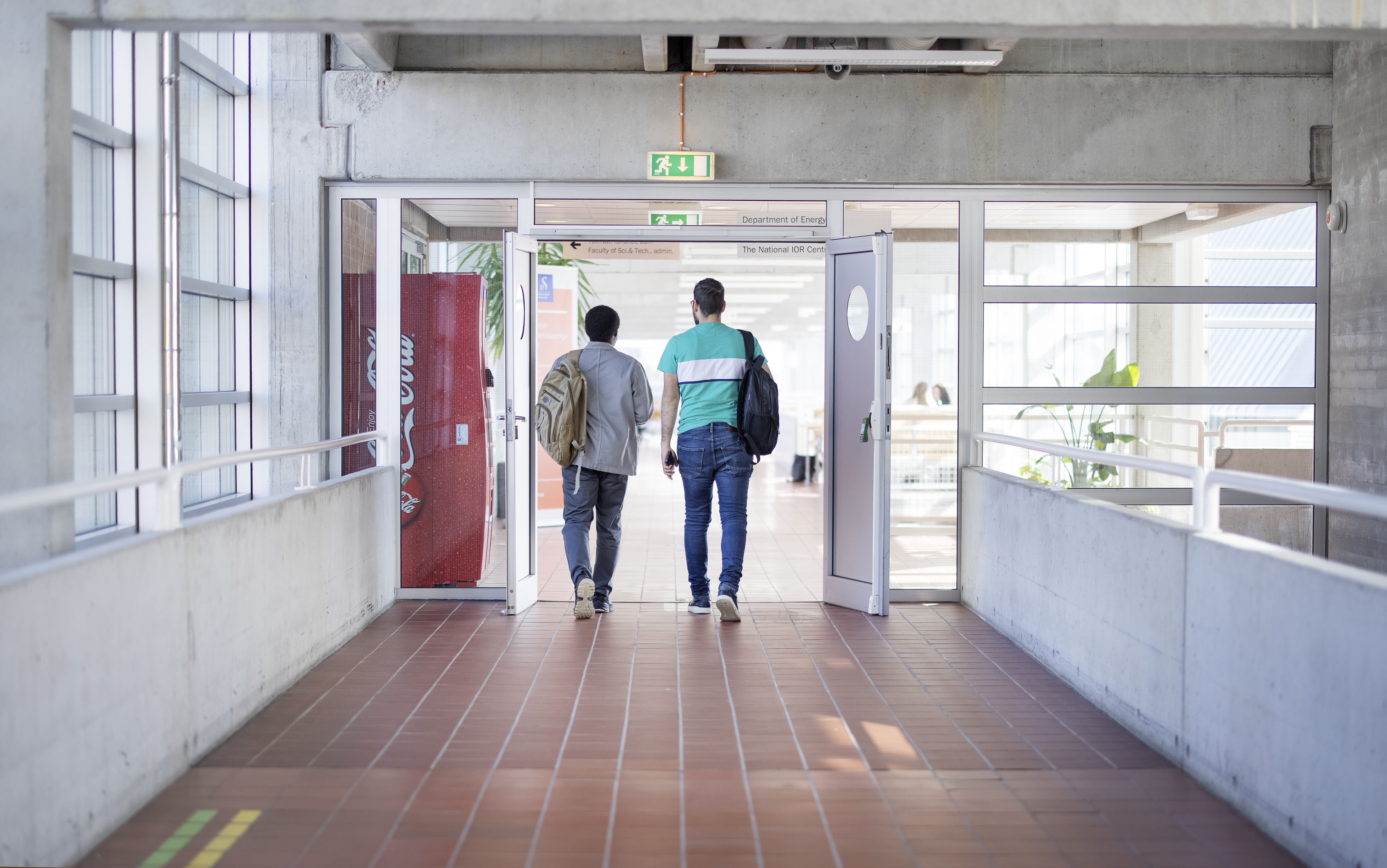To menn går gjennom en korridor.