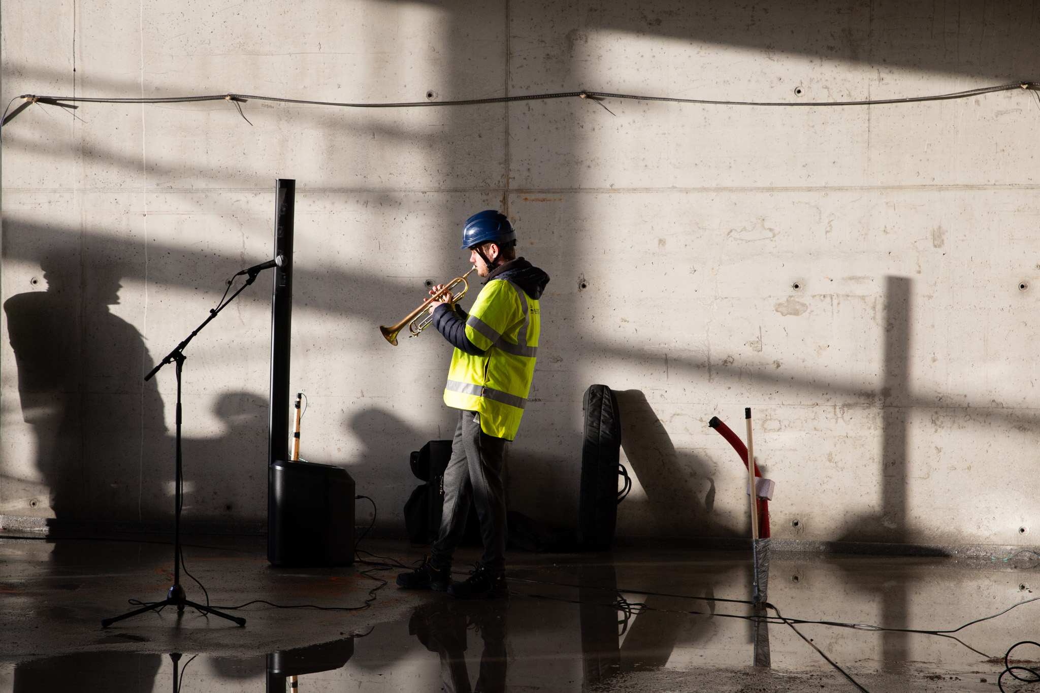 Mann med hjelm og refleksvest spiller trompet i nytt bygg