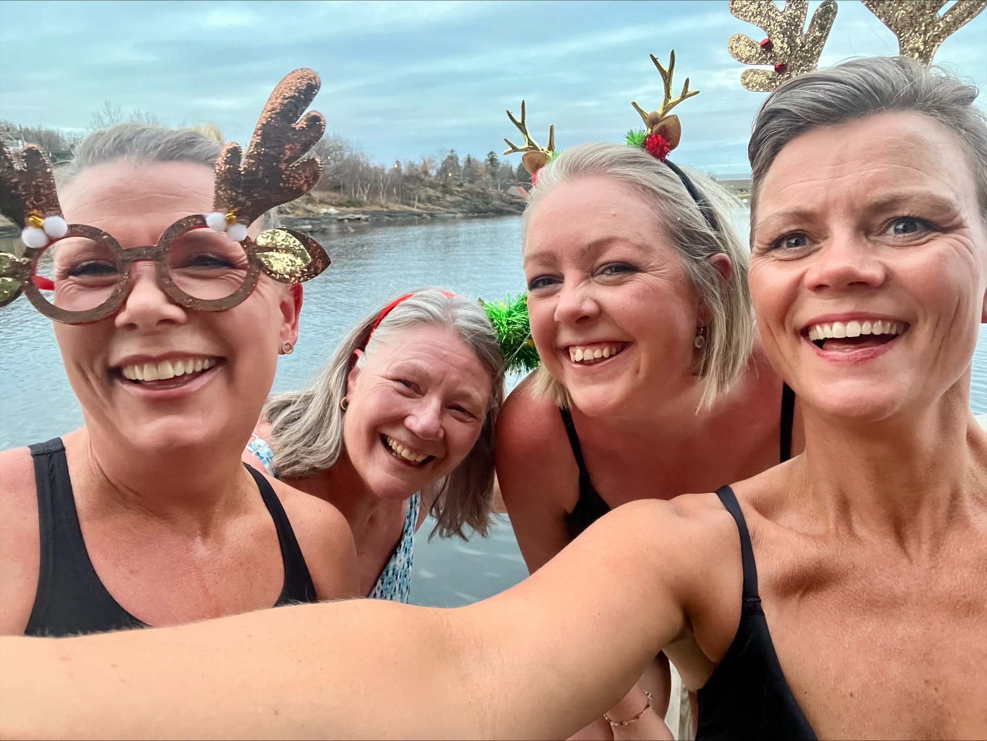 Fire kvinner med julete hårbøyler bader og smiler til kamera 