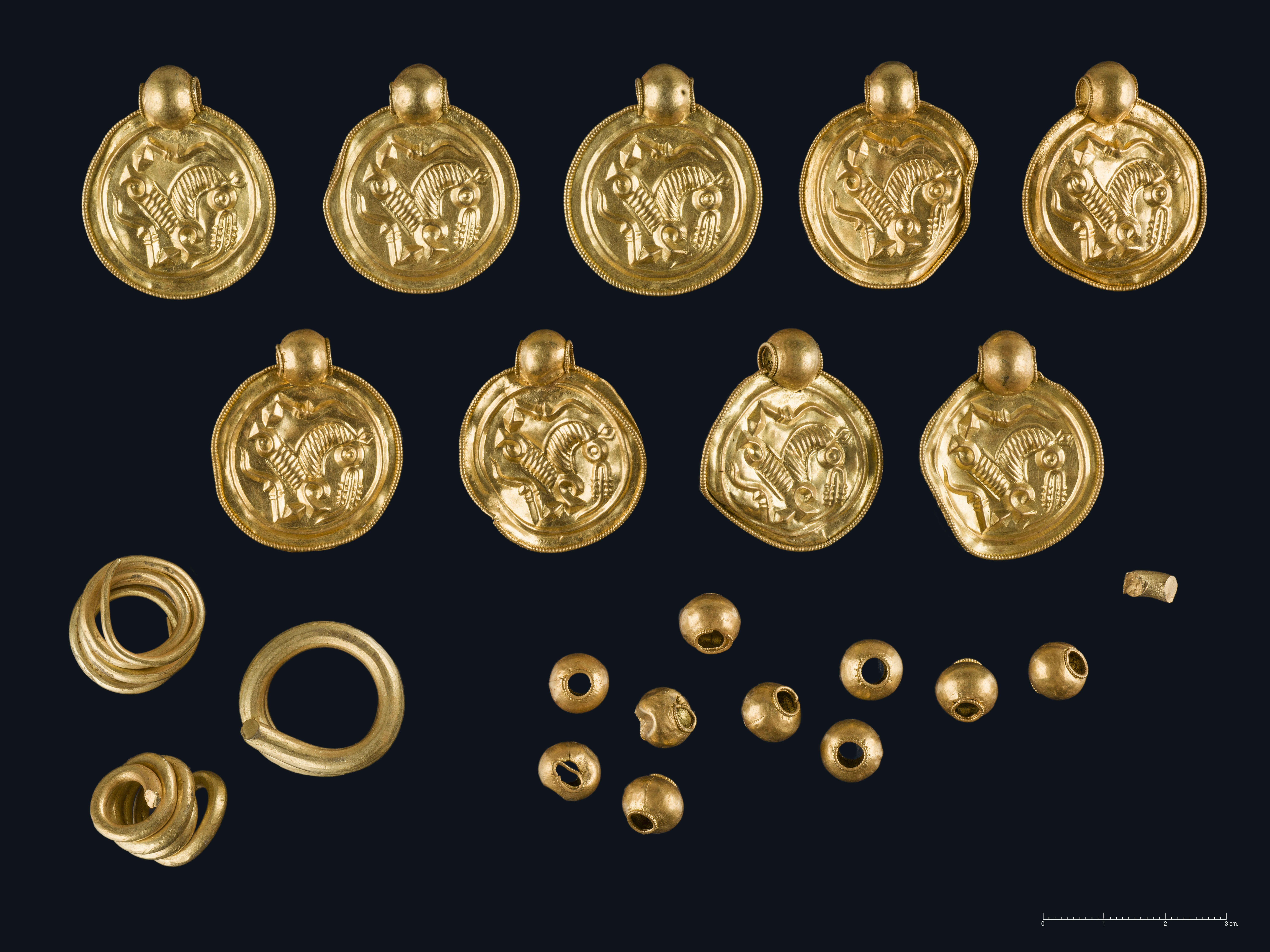 Nærbilder av gullbrakteater som betyr myntlignende smykker med hemper til å henge rundt halsen.