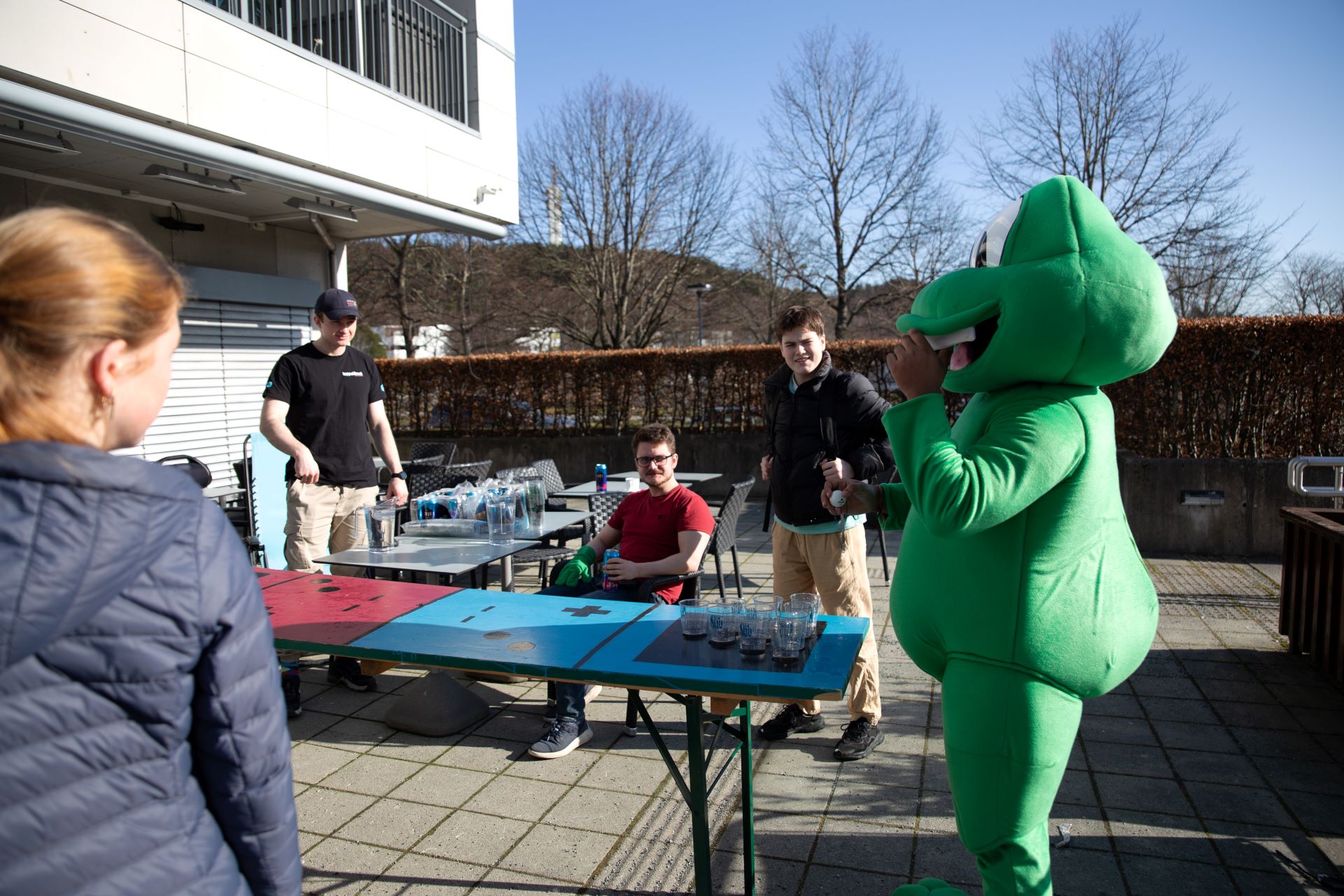 Personer og maskot spiller "Beer-pong" med energidrikk