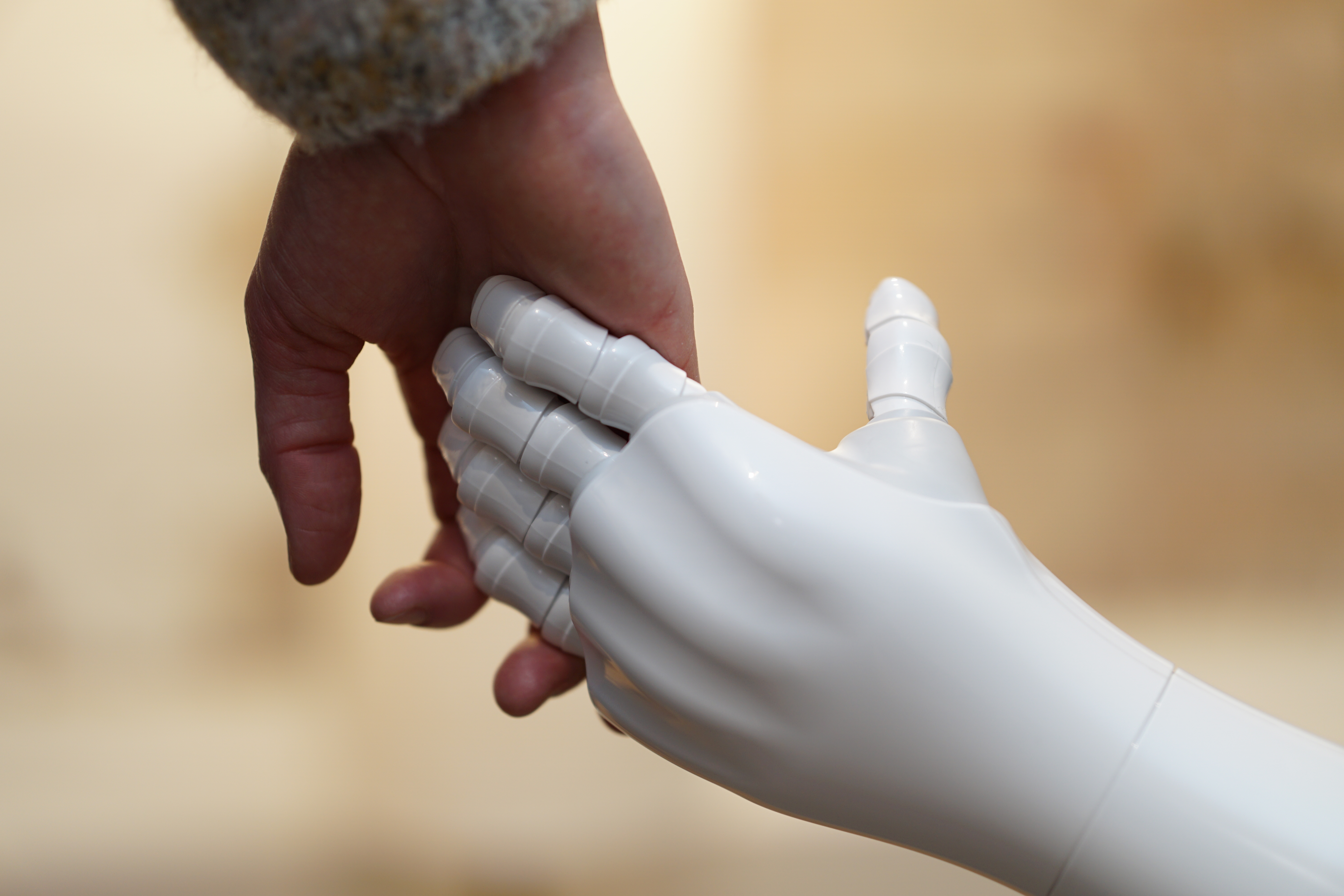En menneskehånd og en robothånd holder hender i et symbol på samarbeid mellom mennesker og teknologi.