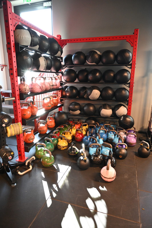 flere cowbells og andre vekter står i ett rødt stativ på SiS sportssenter