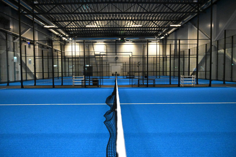 Bilde av blå padelbaner tatt fra nettet, tre baner etter hverandre