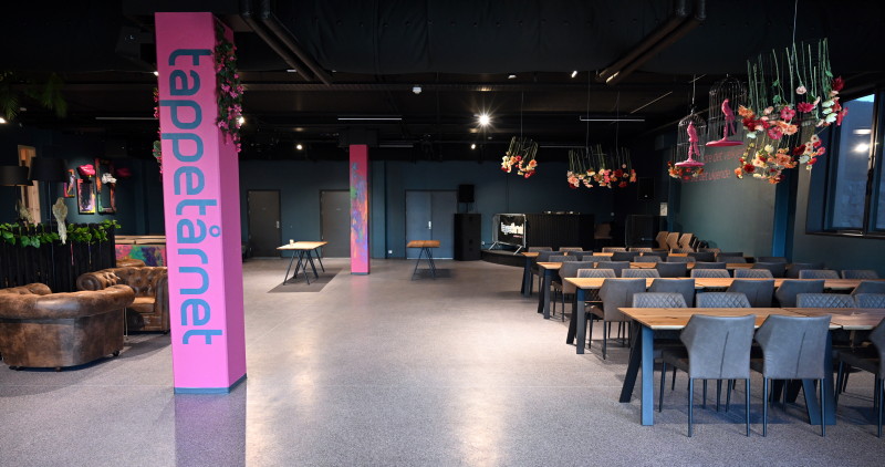 Bilde tatt fra inngangen av tappetårnet, langbord med stoler til høyre i bildet og en rosa søyle med "tappetårnet" skrevet vertikalt