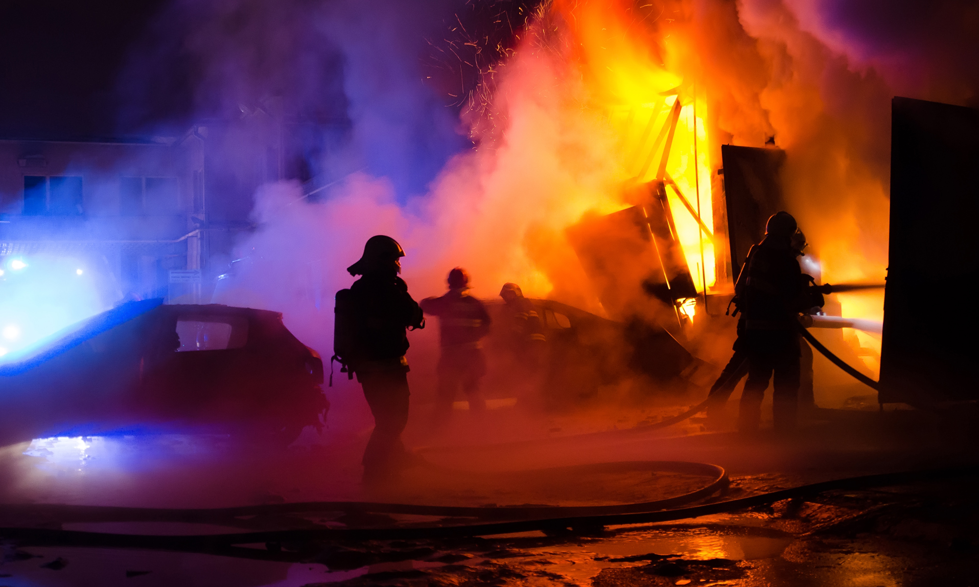 Fire fighters working to put out a fire in a garage. Smoke billowing.