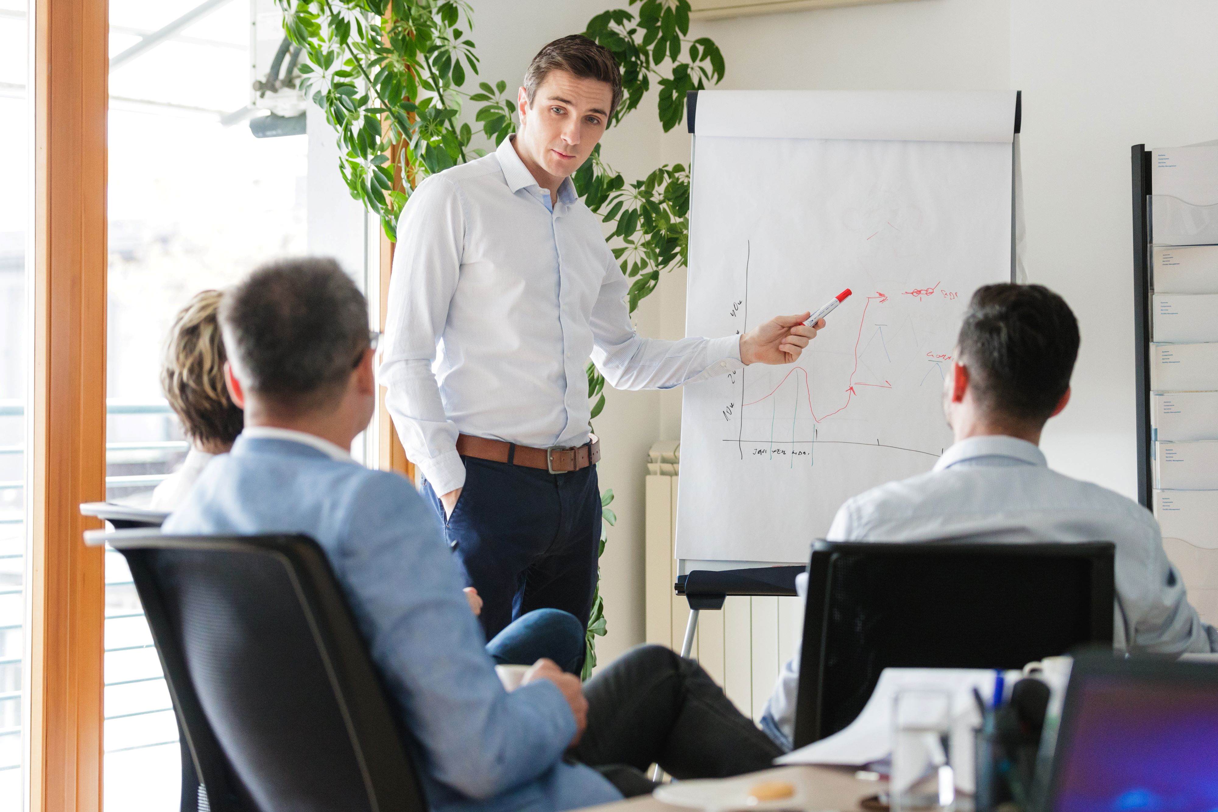 Mann står med whiteboard og har en presentasjon foran en gruppe mennesker