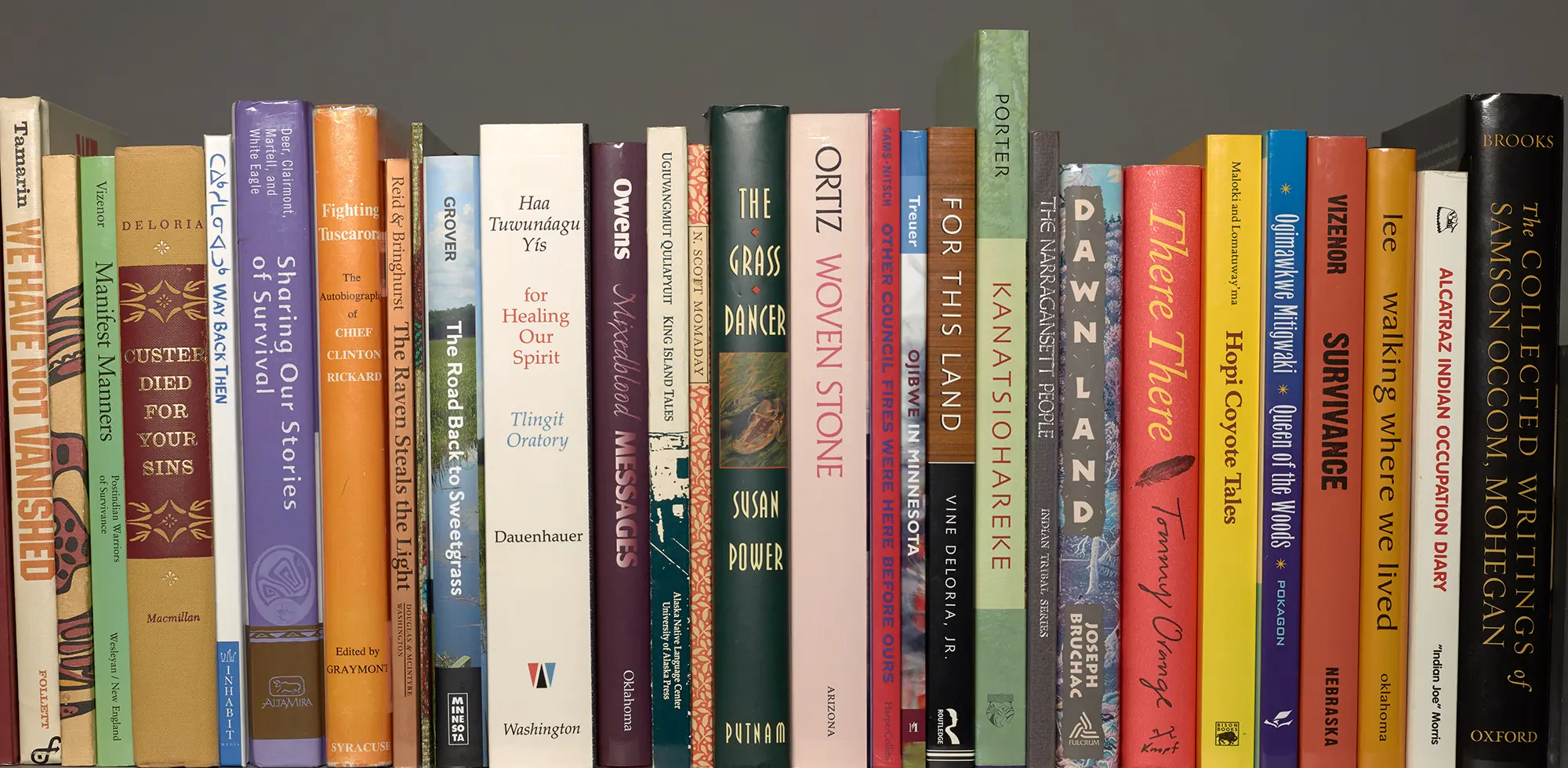 A shelf in the KWEC archive of Native American Literature displaying the spines of books by numerous Native authors