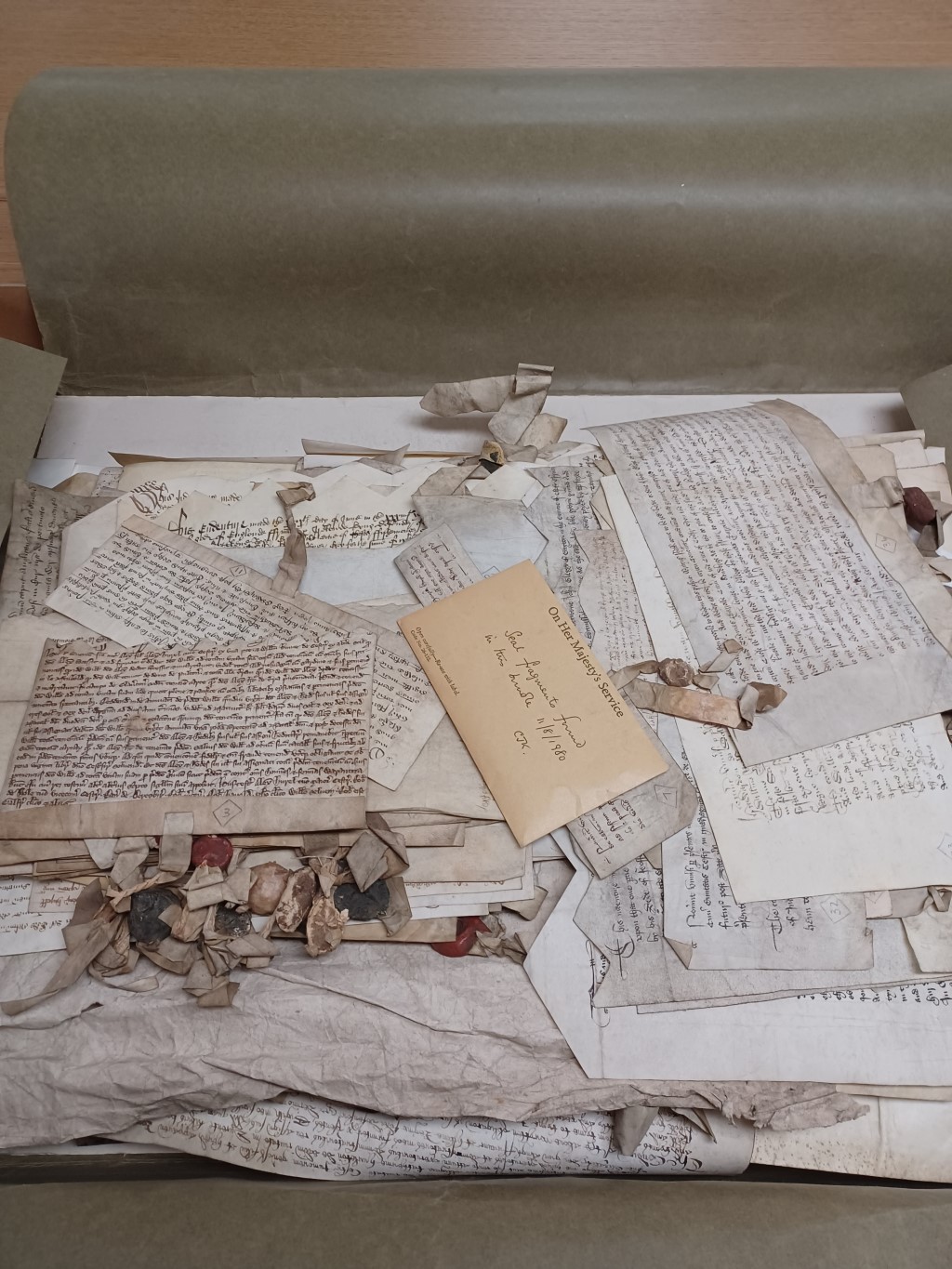 Medieval documents piled up on top of each other in an archive box