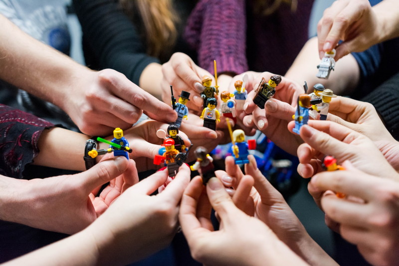 Flere personer som holder legofigurer i hendene