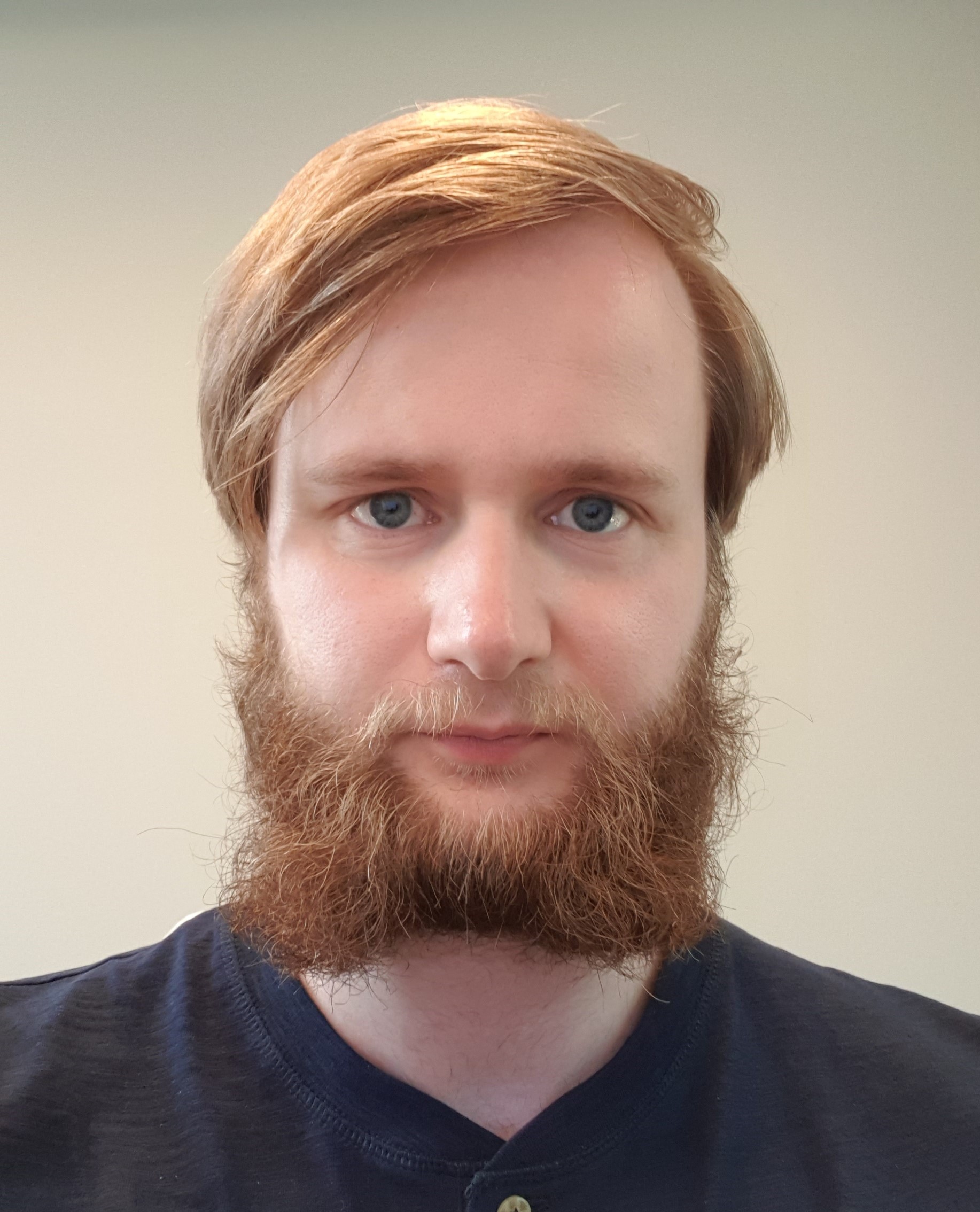 mann med rødlig hår og skjegg ser i kamera