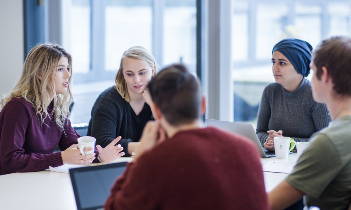 Five students sitting around a table 