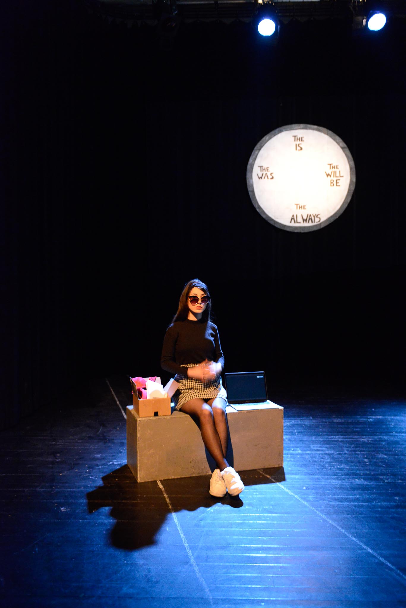Dramastudent sitter på en scene ikledd kostyme.
