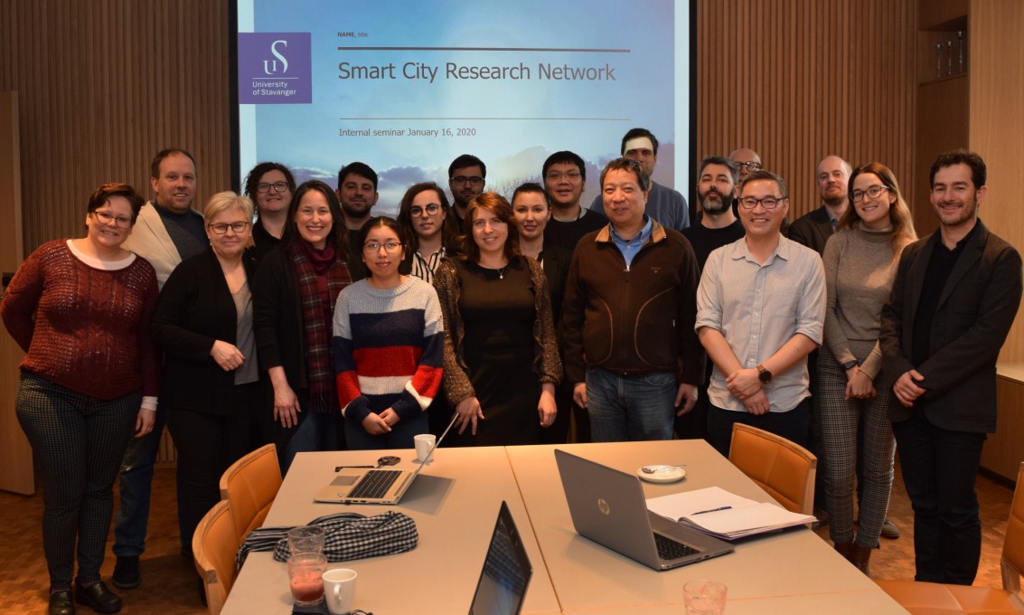 19 forskere samlet foran storskjerm med smartby-presentasjon