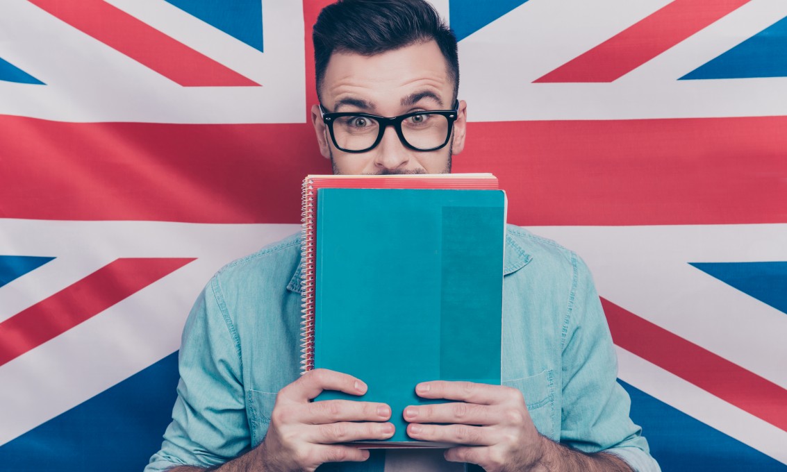 Portrett av spent mann som holder fargerike bøker i hendene, engelsk flagg i bakgrunnen