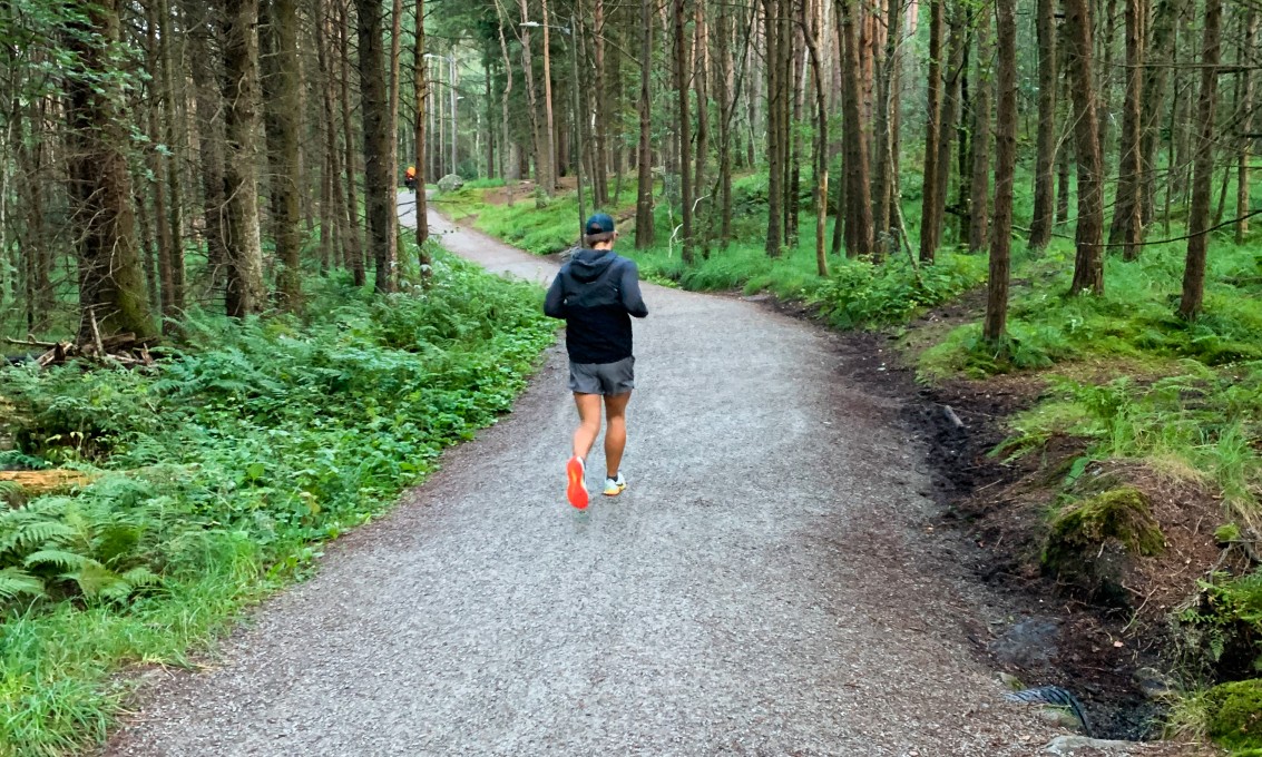 En mannlig jogger på grusvei i en skog