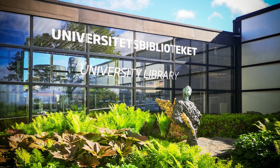 Grønt område foran glassbygg med skriften "Universitetsbiblioteket" skrevet på