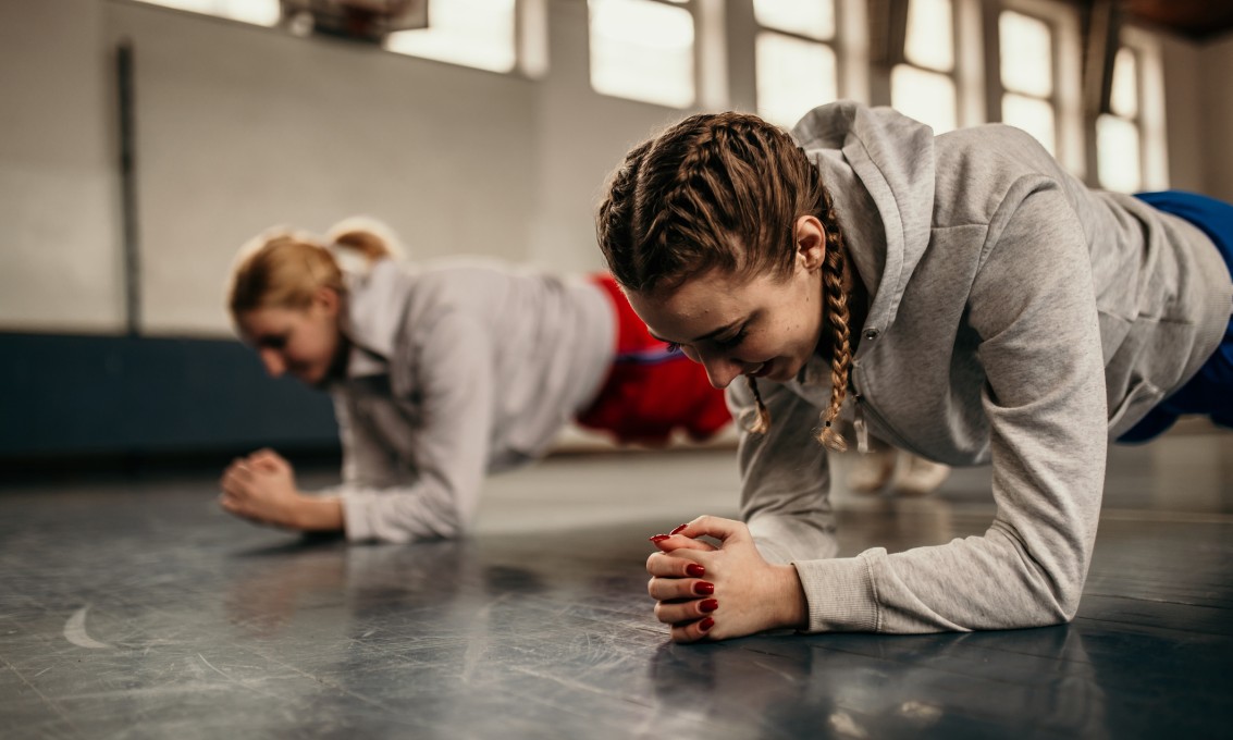 To jenter trener styrketrening i gymsal