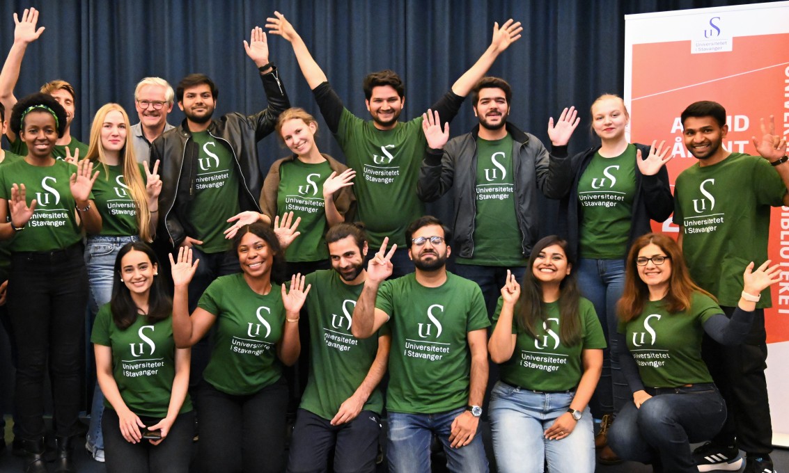 15 studenter med grønne UiS-t-skjorter jubler og vifter med armene