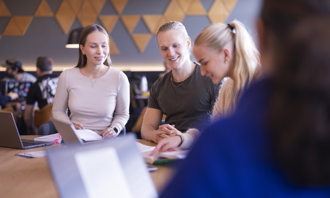 Flere studenter sitter bed et bord og jobber. Foto.