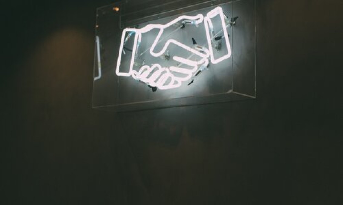 neonskilt med to hender i et håndtrykk