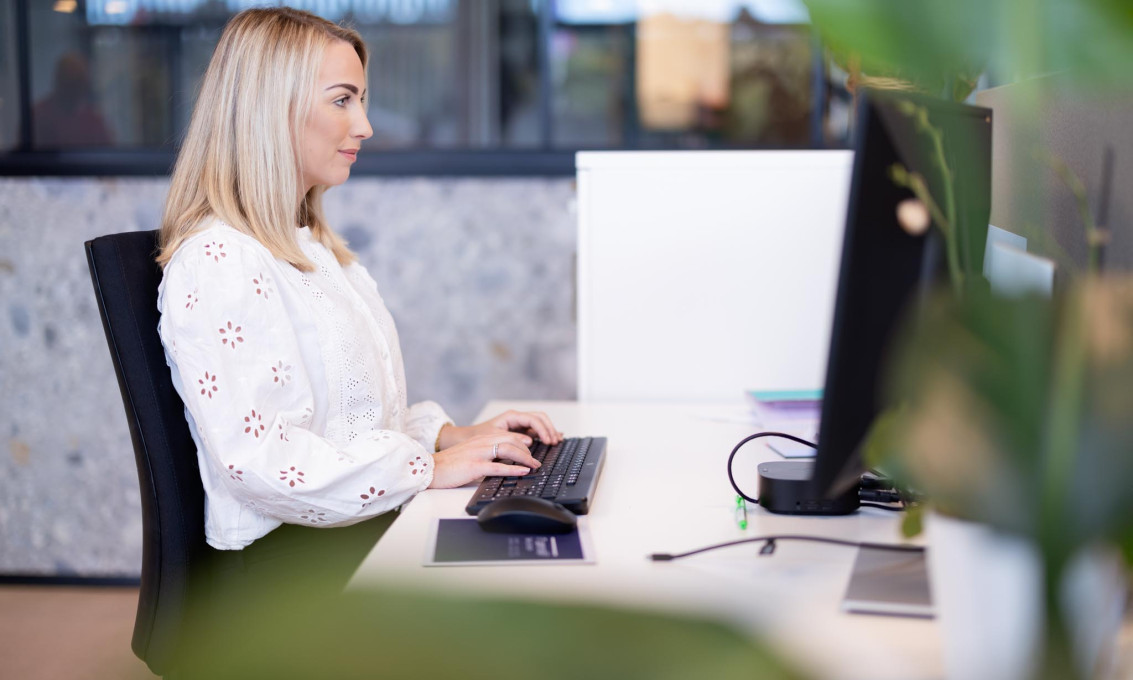 En person sitter ved en PC og jobber.
