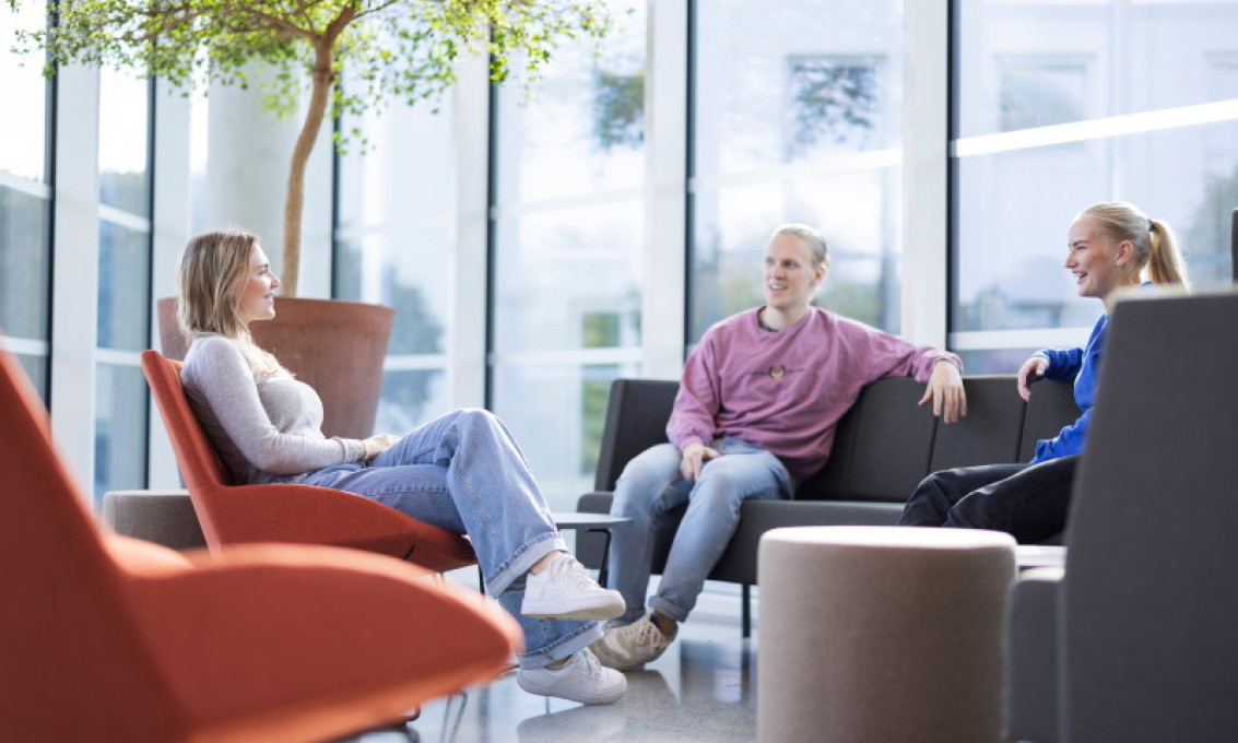 Tre studenter sitter i sofagruppe